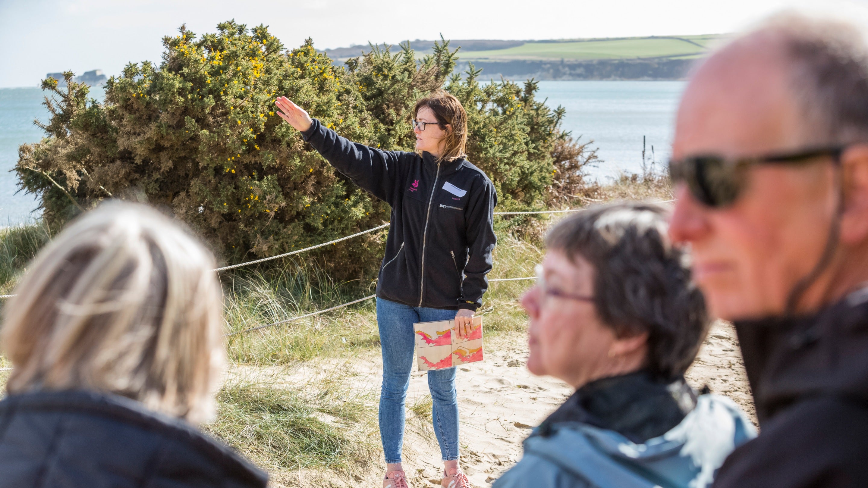 A staff members talks to a group of staff and volunteers during a training day on the beach at Studland Bay, Dorset