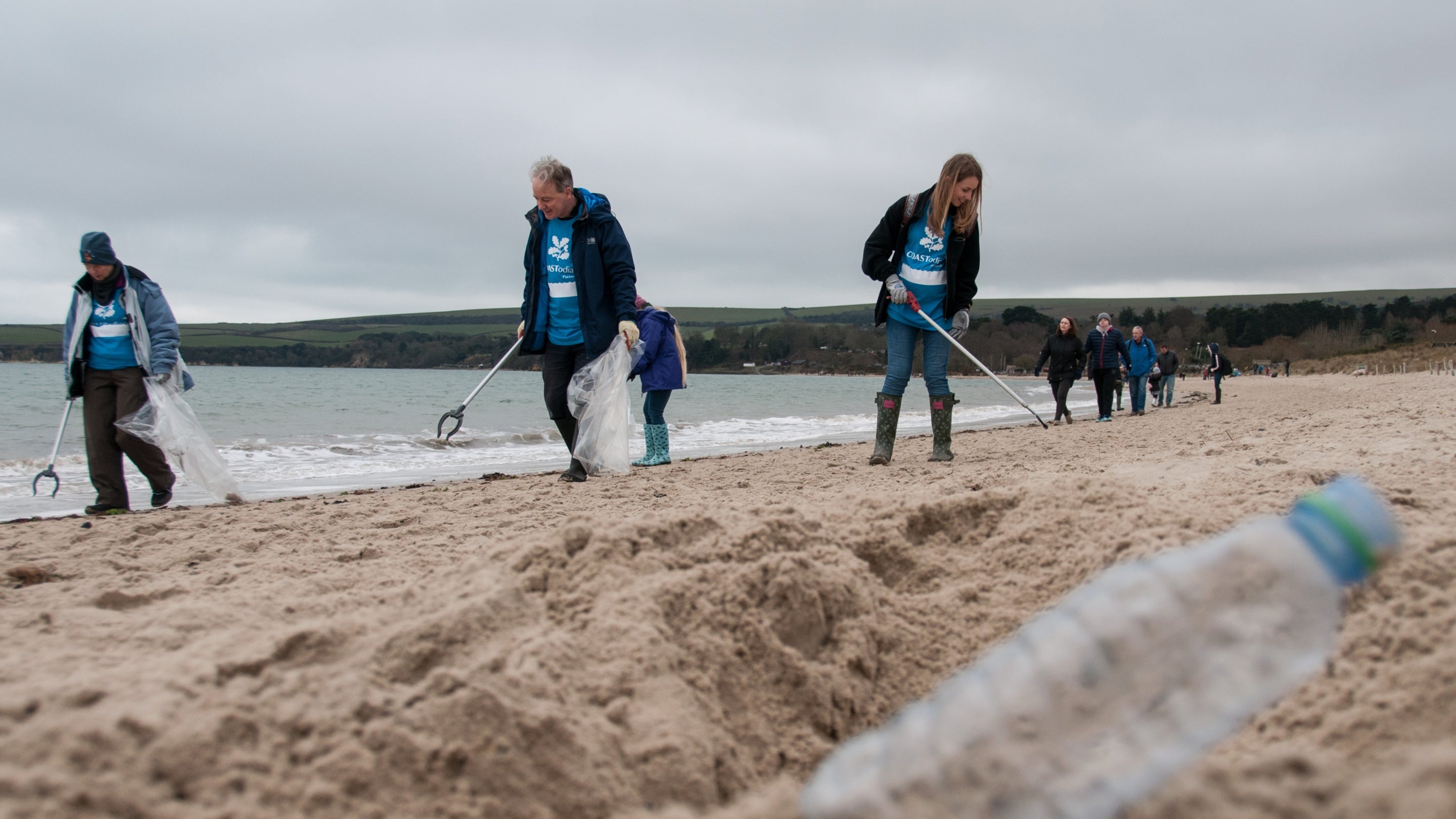 A group of volunteers and staff members pick up litter on the beach at Studland Bay, Dorset
