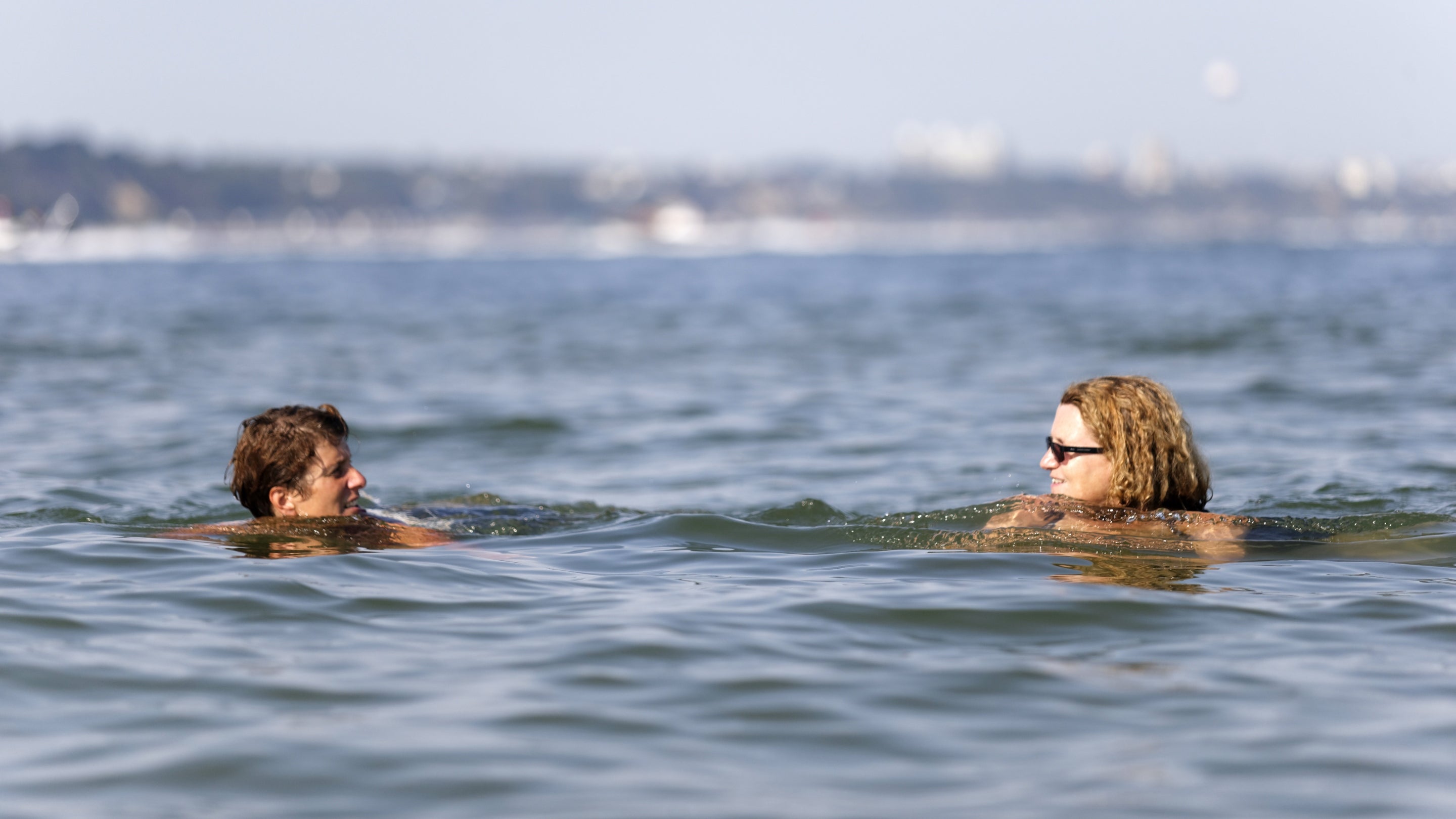 Two people swimming in the sea at Shell Bay, Studland, Dorset