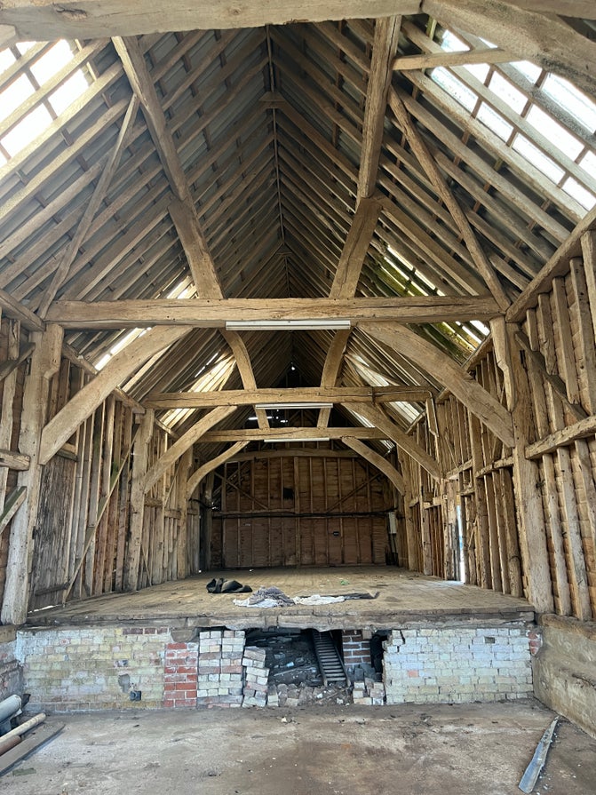 The interior of the 19th century barn at Ward's Hurst Farm showing timber beams and raised floor