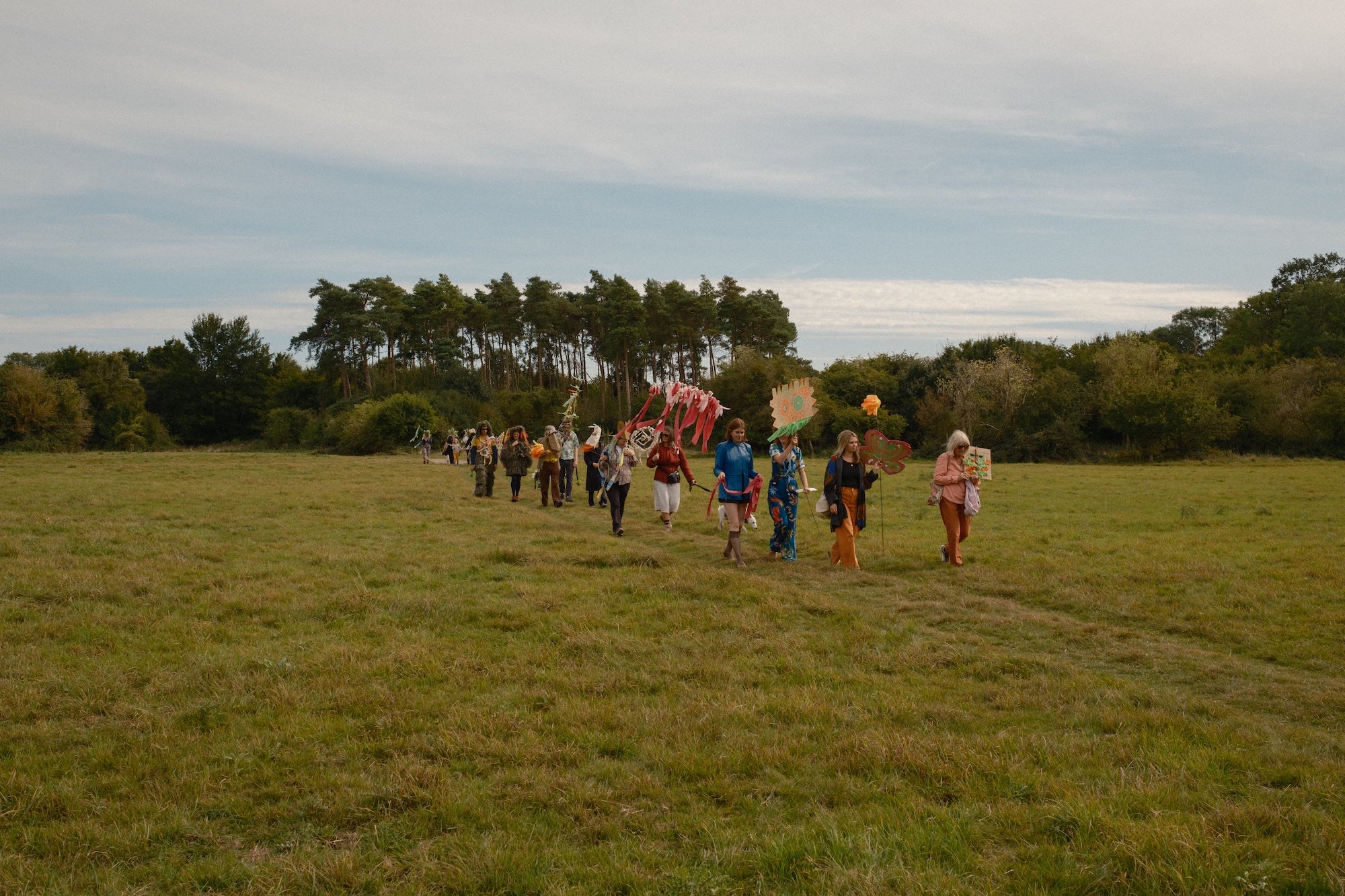 A group of people dressed in bright colours parade across an open plain at Hatfield Forest