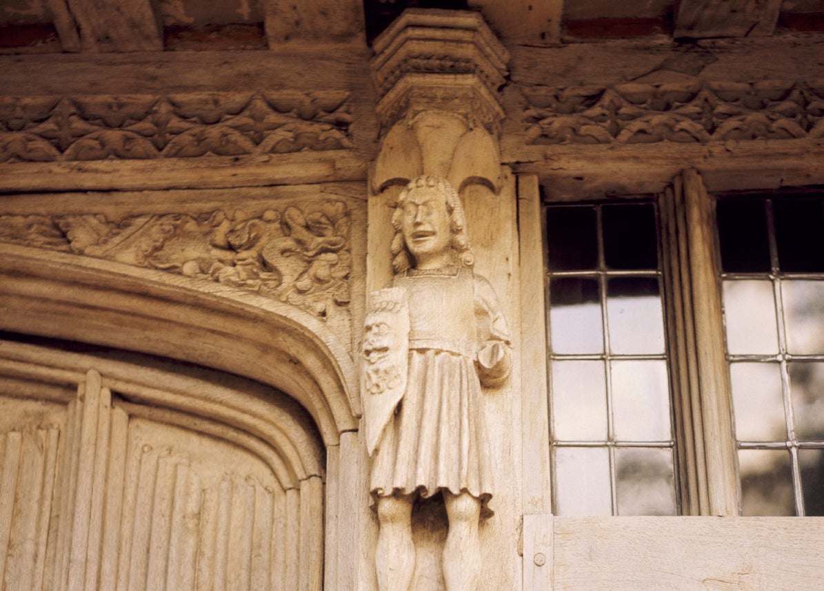 Detail of a smiling carved figure on the portal at Paycocke's House, believed to be a statue inspired by a mummer's play