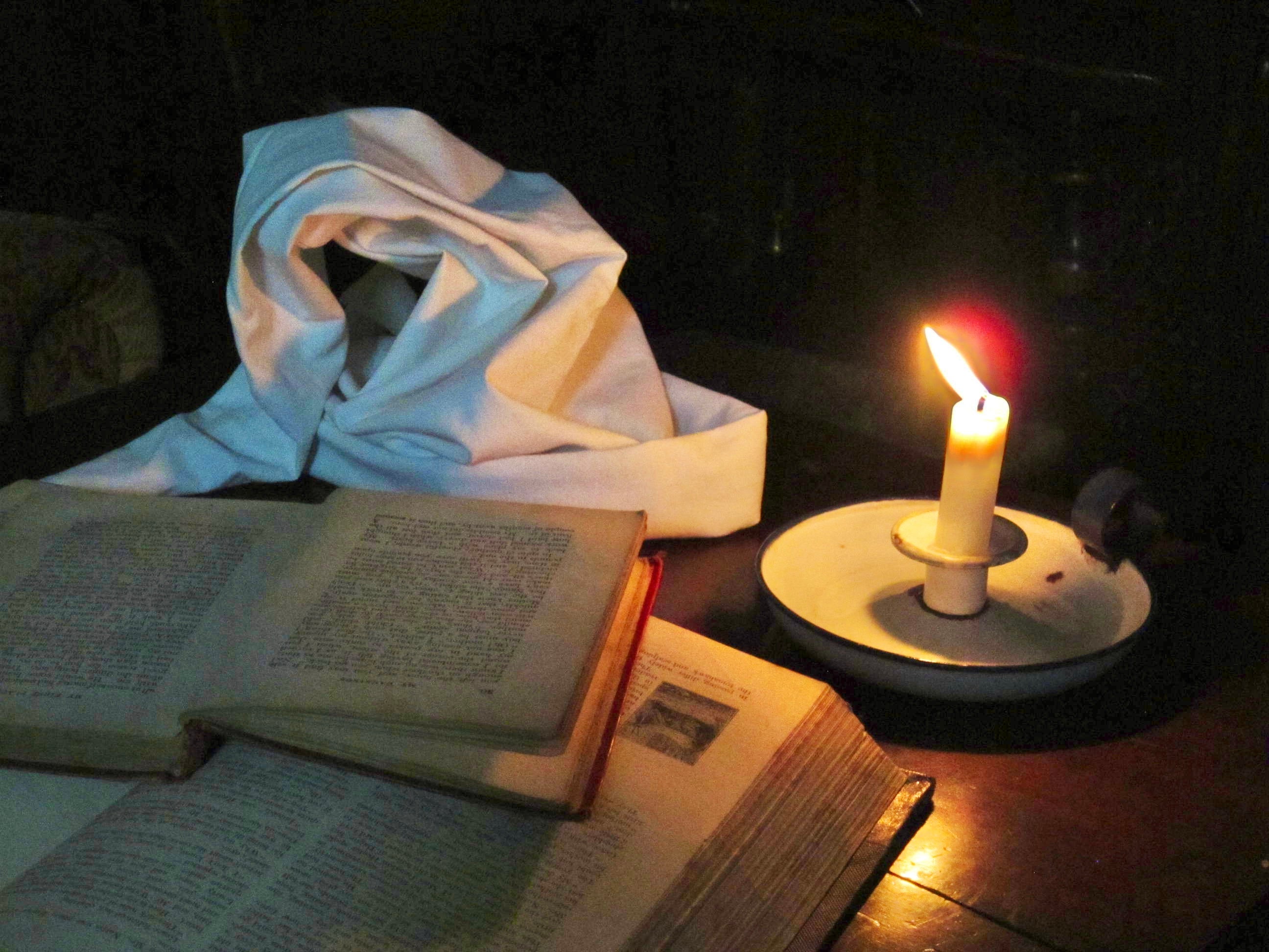 A candle flame illuminates open books