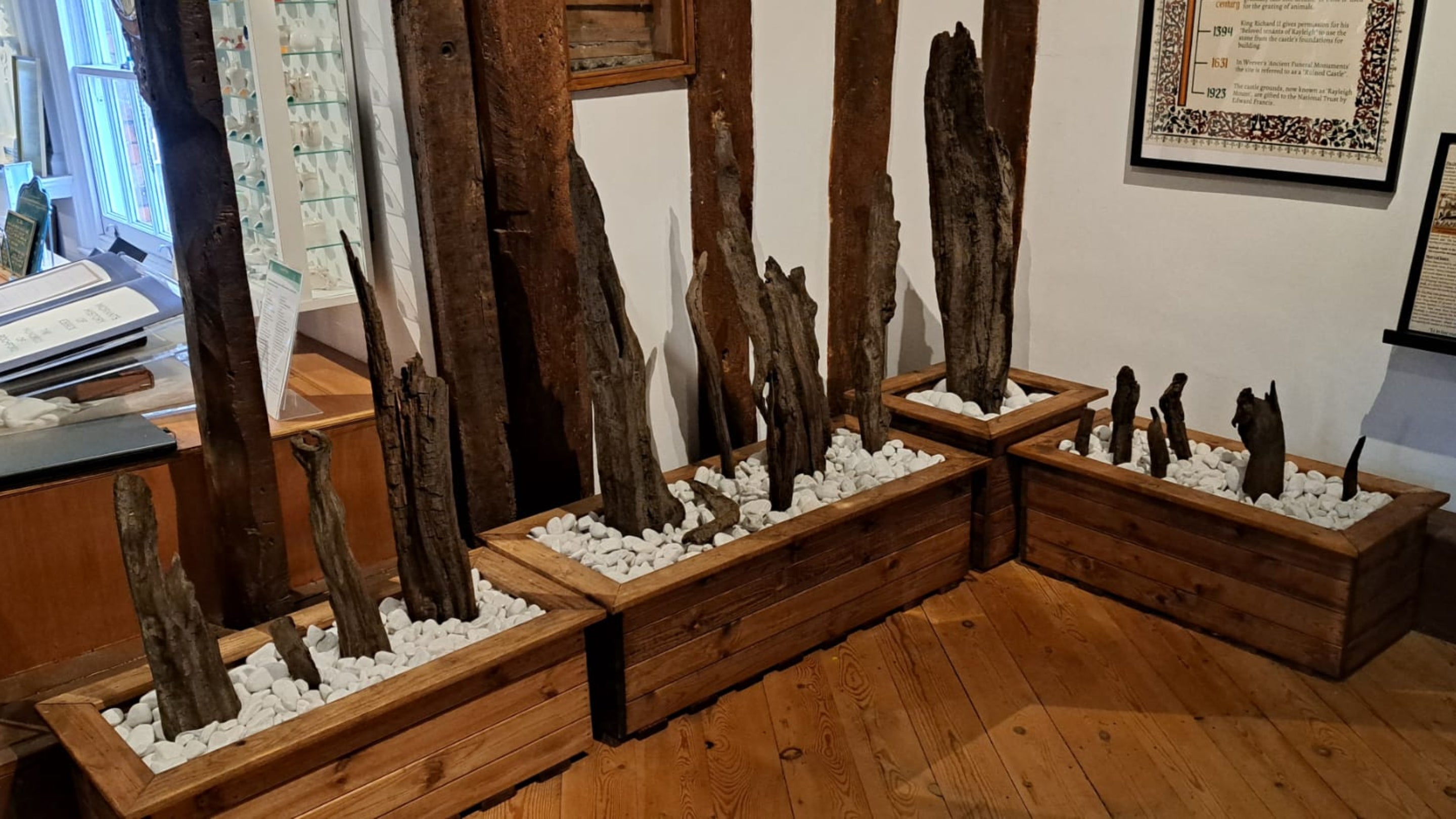 Timbers excavated at Rayleigh Mount on display at Rayleigh Town Museum, mounted upright, in troughs of small stones