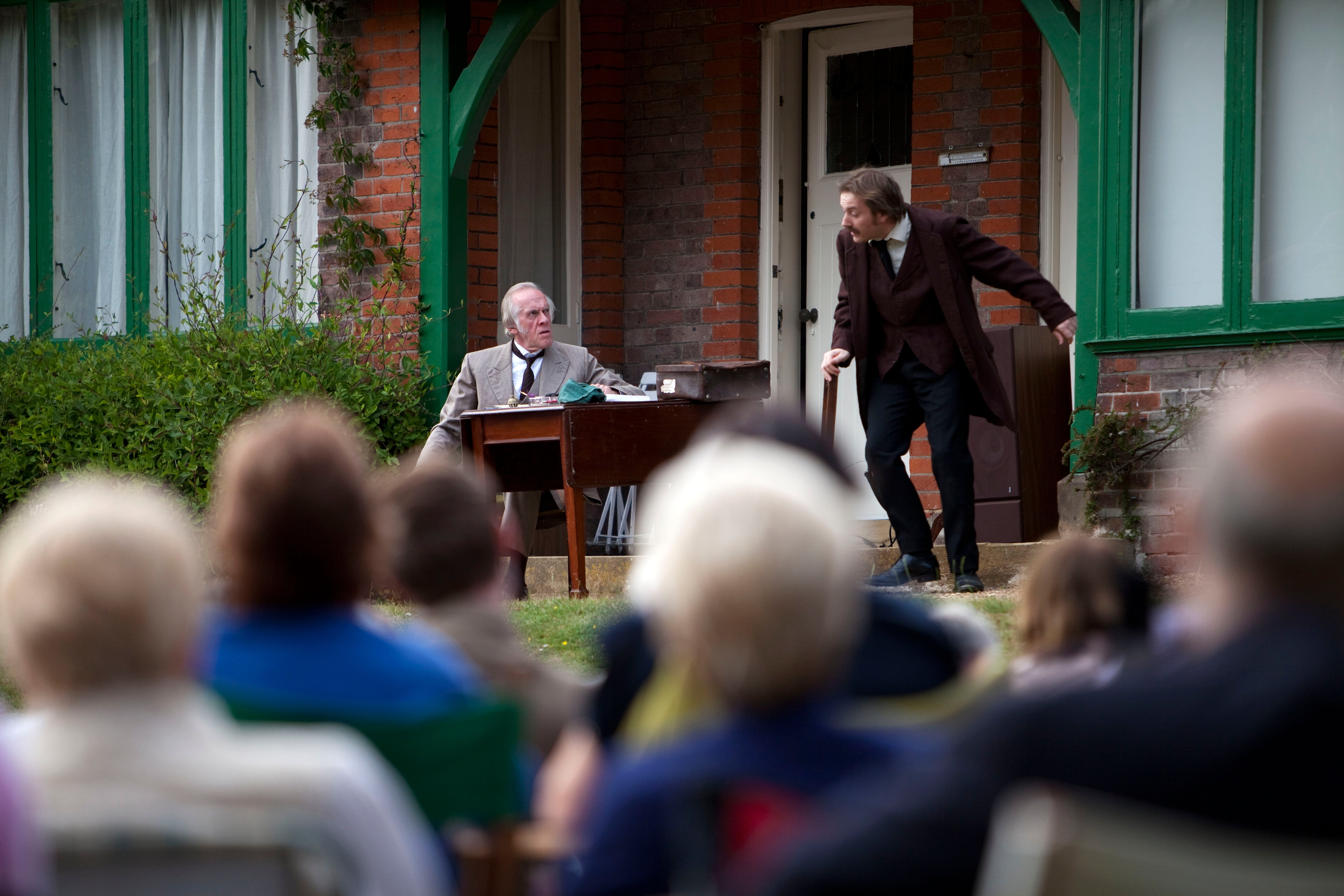 Audience watching the play at an outdoor theatre event at Shaw's Corner, Hertfordshire.