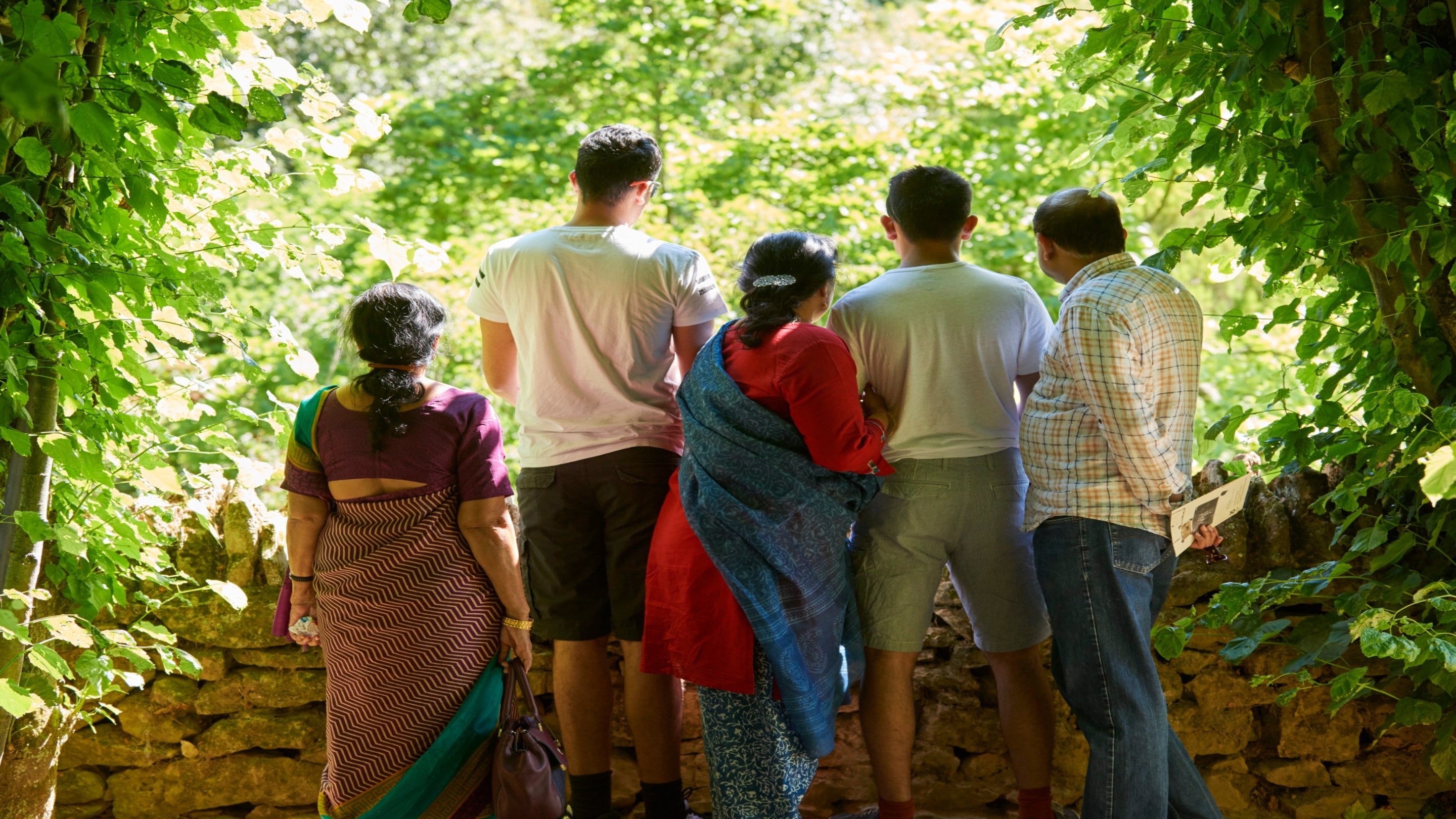 A family enjoying the shade of the lime bower at Hidcote