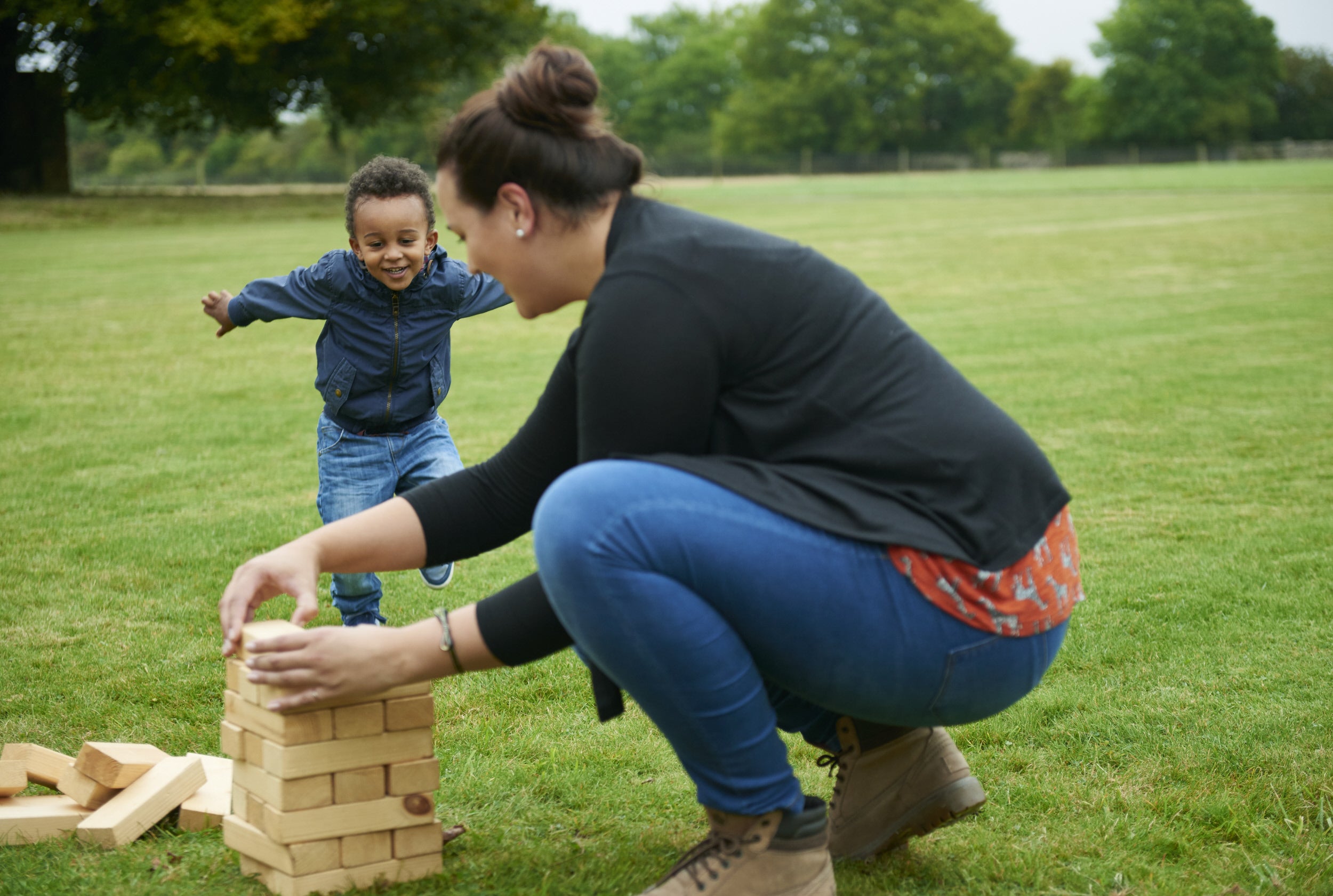 A lady and child playing giant jenga on the lawn at Lodge Park, Gloucestershire
