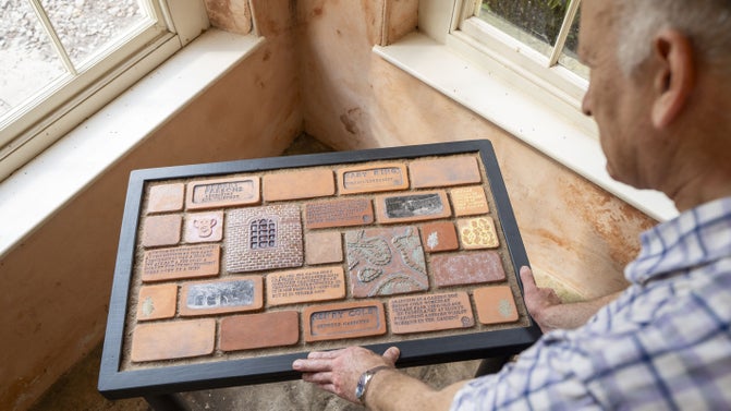A person looking down at a collection of small terracotta tablets