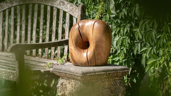 A carved wooden head on a stone garden bench