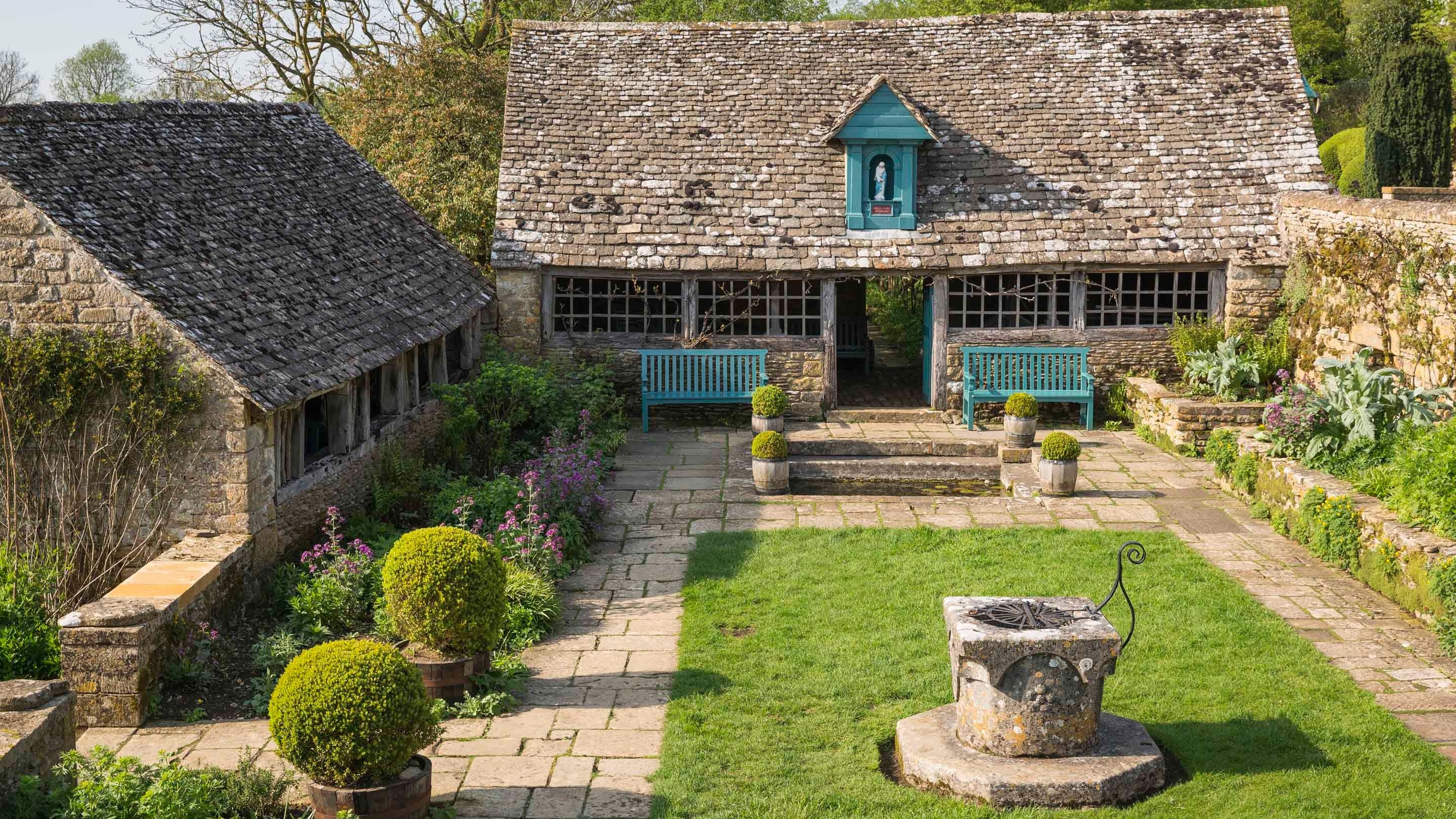 A view of the Well Court and the Sancta Maria Byre, with a shrine to the Virgin Mary mounted on the gable, at Snowshill Manor, Gloucestershire