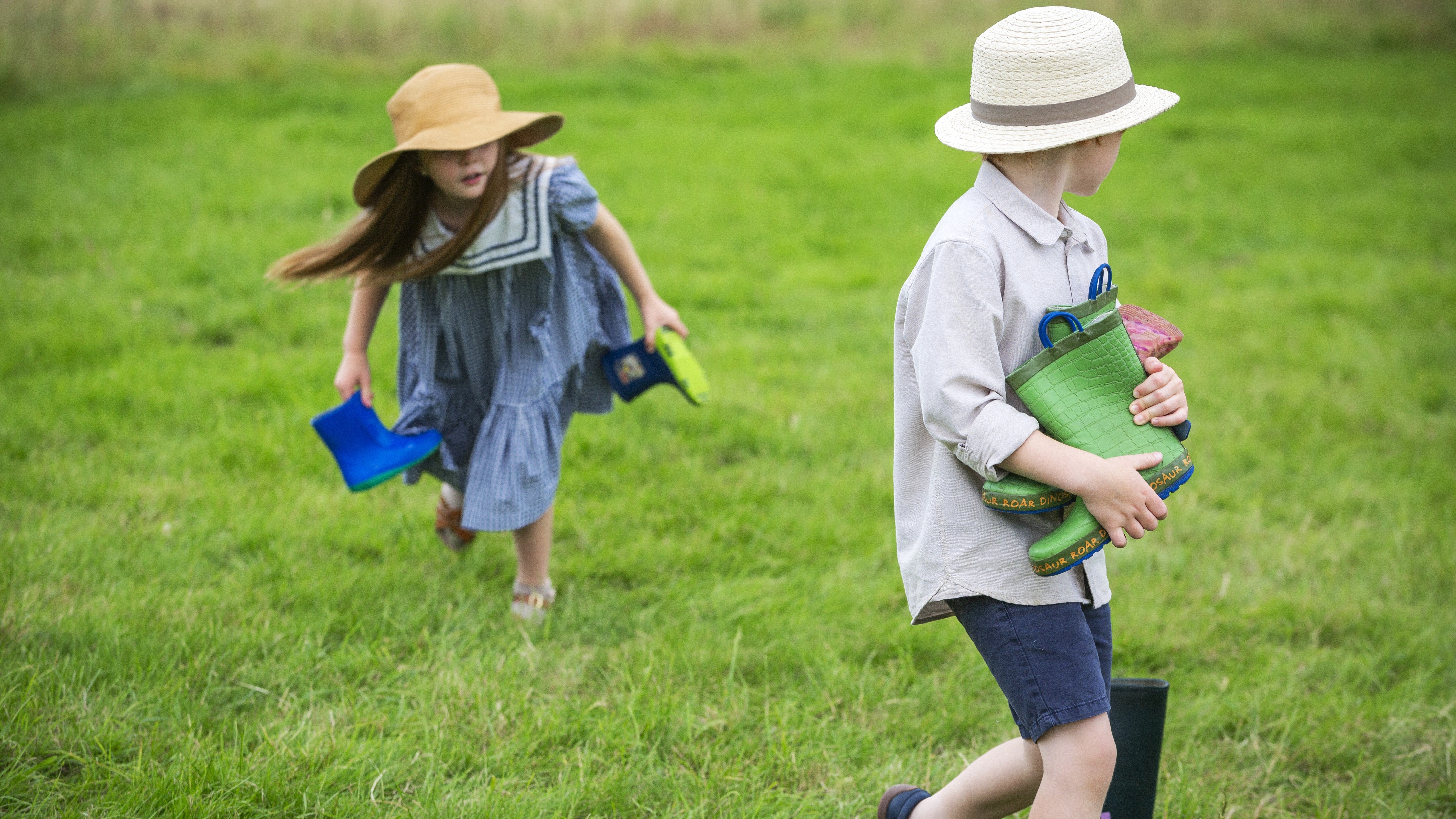 Two children collecting wellington boots in a field