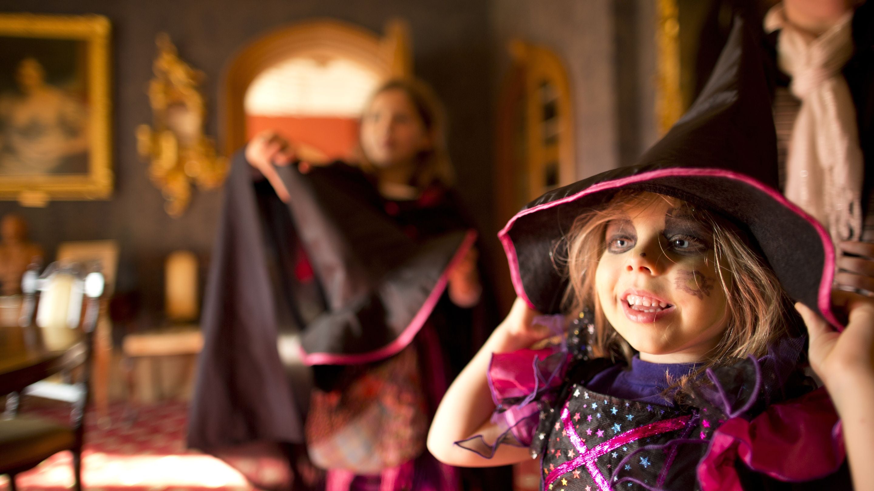 Young girl in witch's costume with witch's hat inside Hughenden Manor