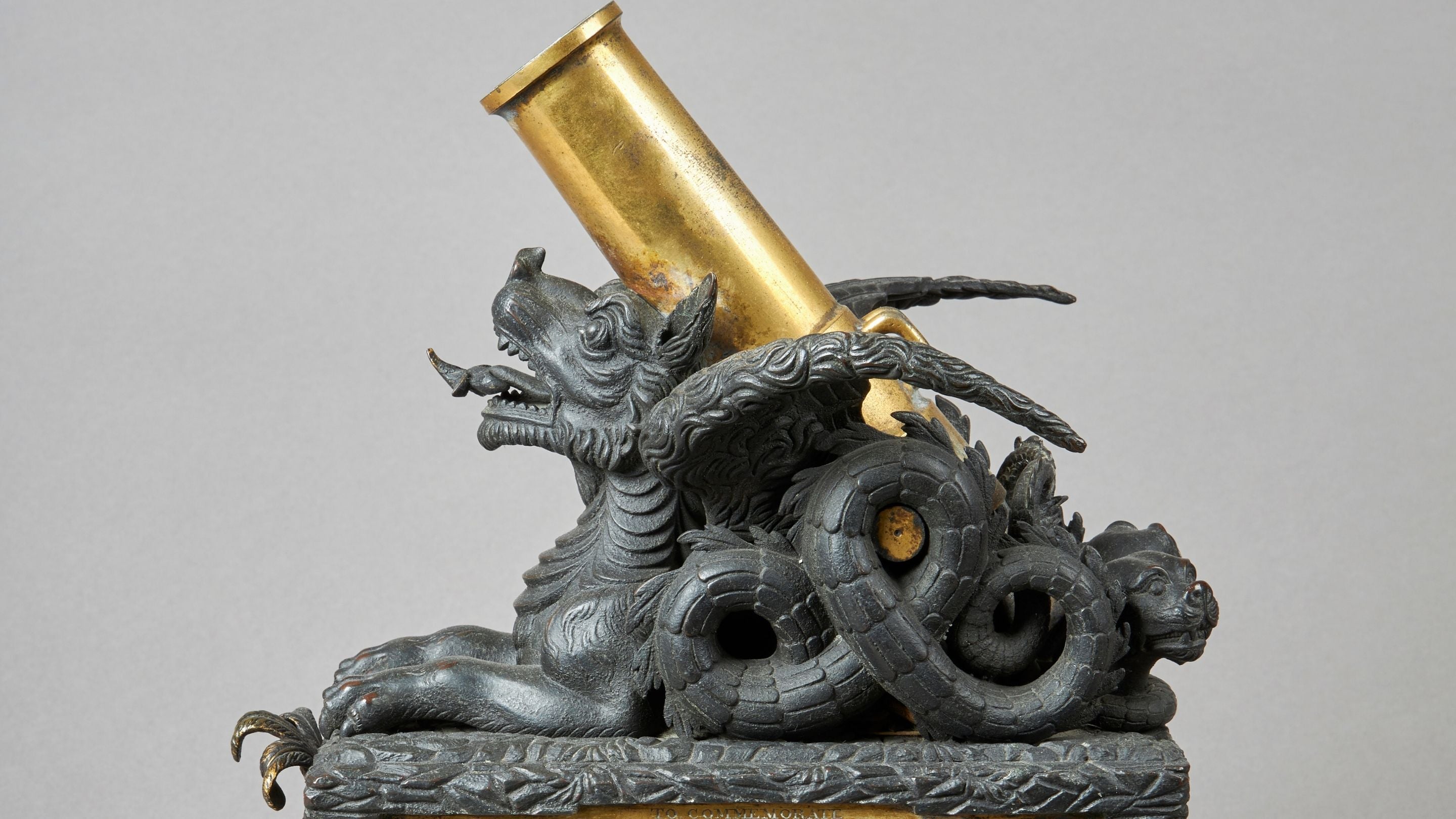 Close up of inkstand featuring an Asian-style grey dragon with wings and curled tail curved over a gold coloured mortar on its back