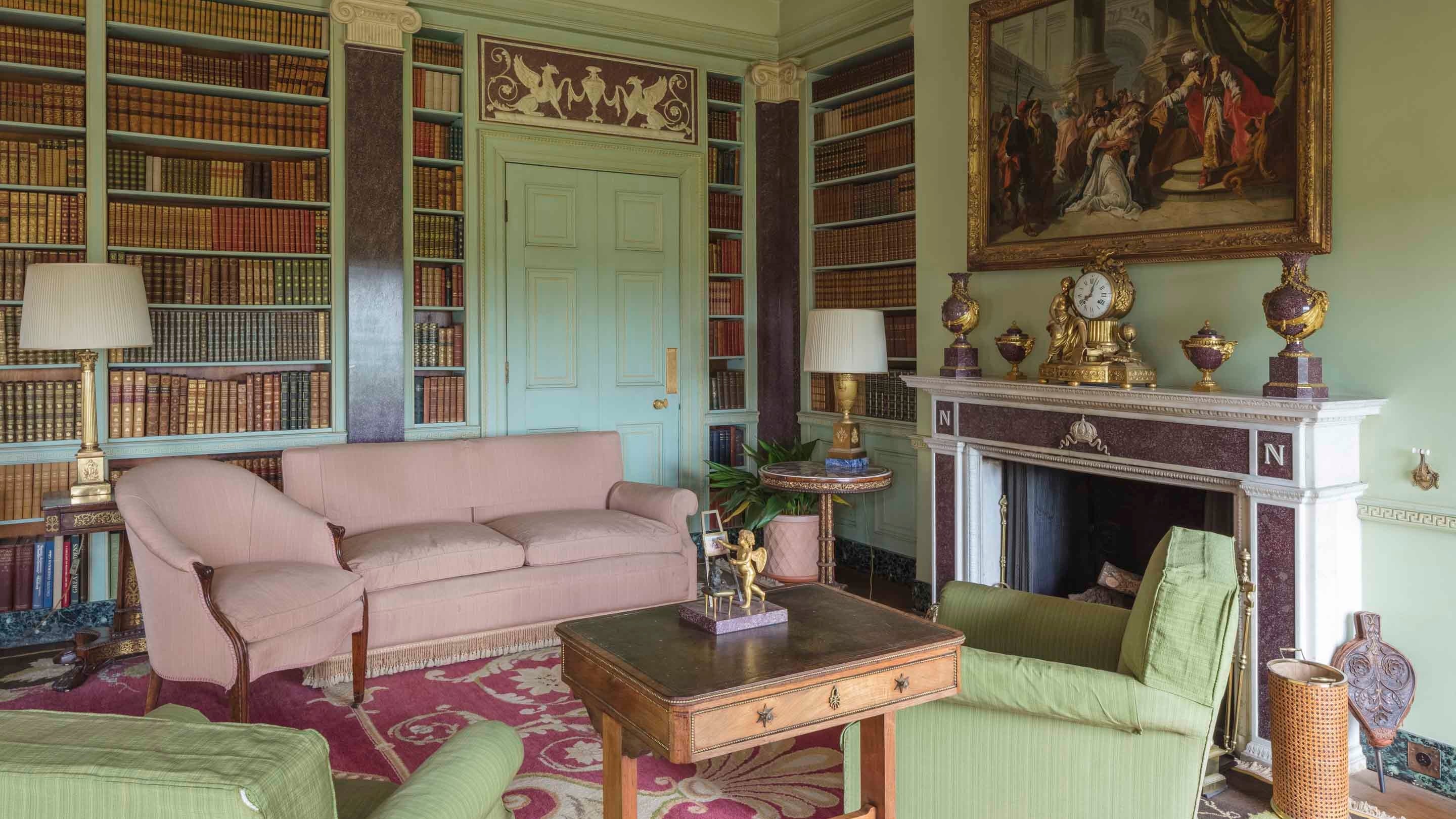 The Library at Hinton Ampner, Hampshire, with pale green walls and furniture, bookcases and a pink patterned carpet