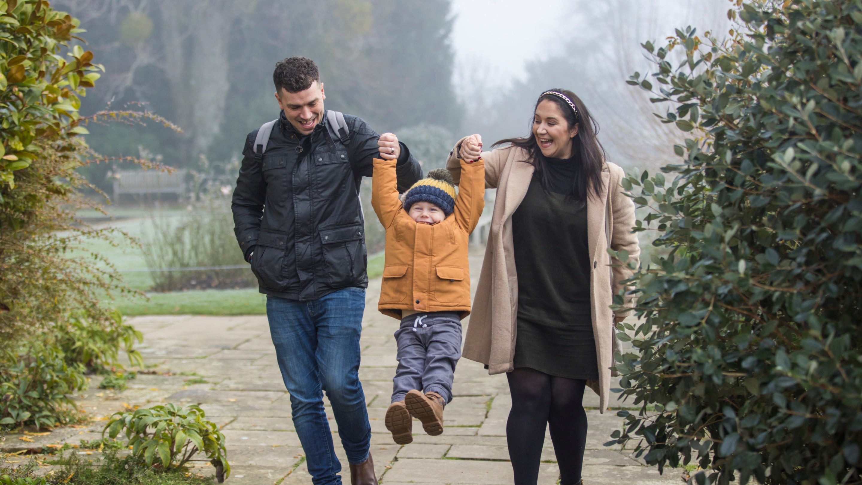 A family exploring the gardens in winter at Hinton Ampner, Hampshire with trees in the background