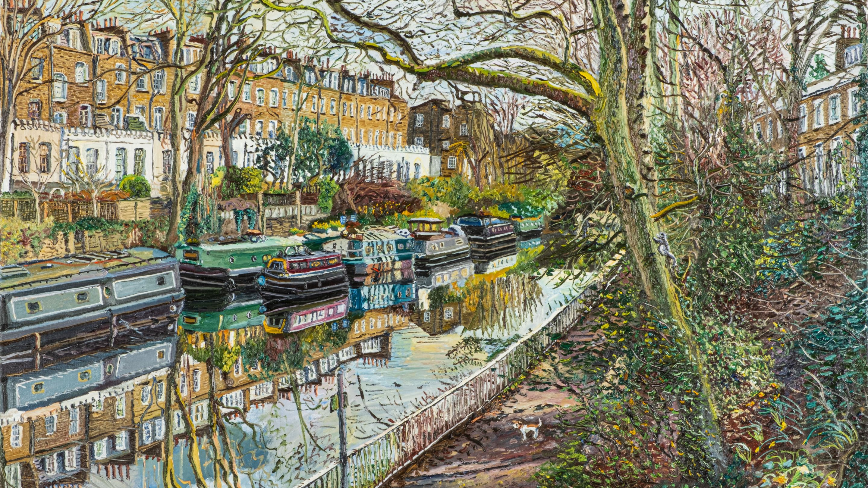 A tree-lined canal in London with traditional narrow boats and edged by townhouses which are reflecting in the water