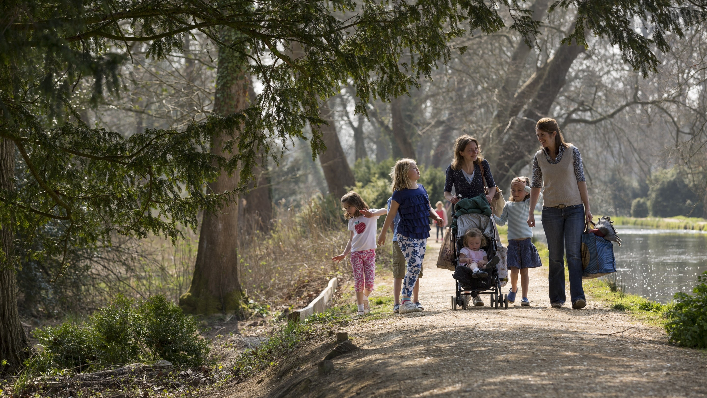 A family walking beside the river in the gardens at Mottisfont, Hampshire