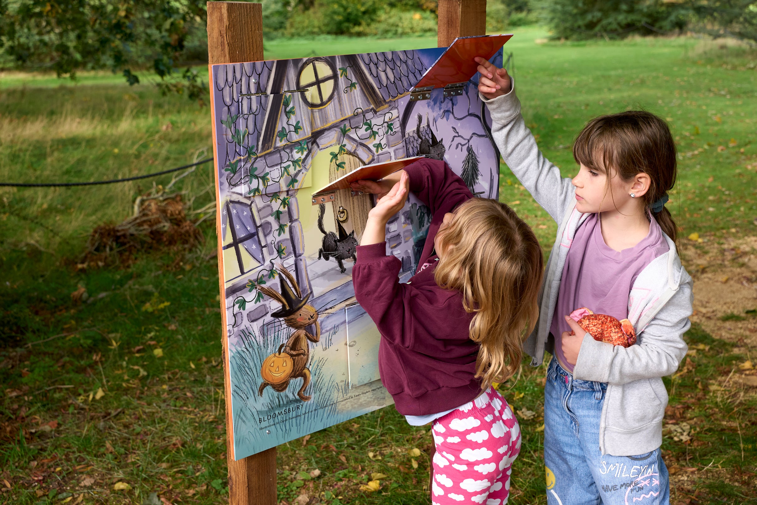 Two girls lift flaps on an activity board at The Vyne.