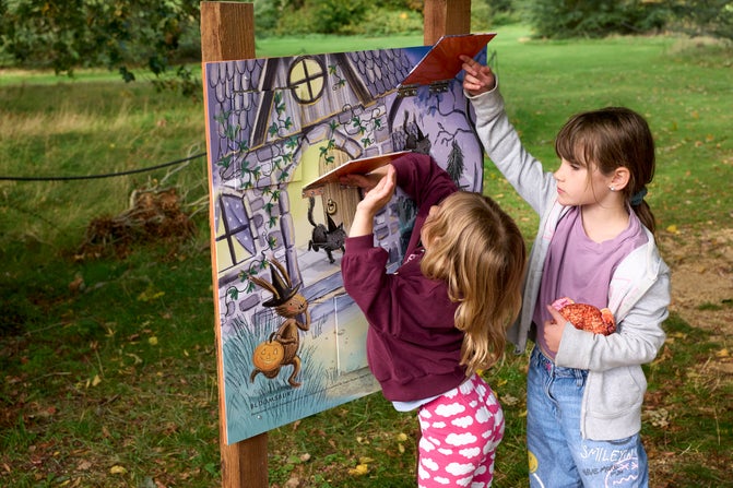 Two girls lift flaps on an activity board at The Vyne.