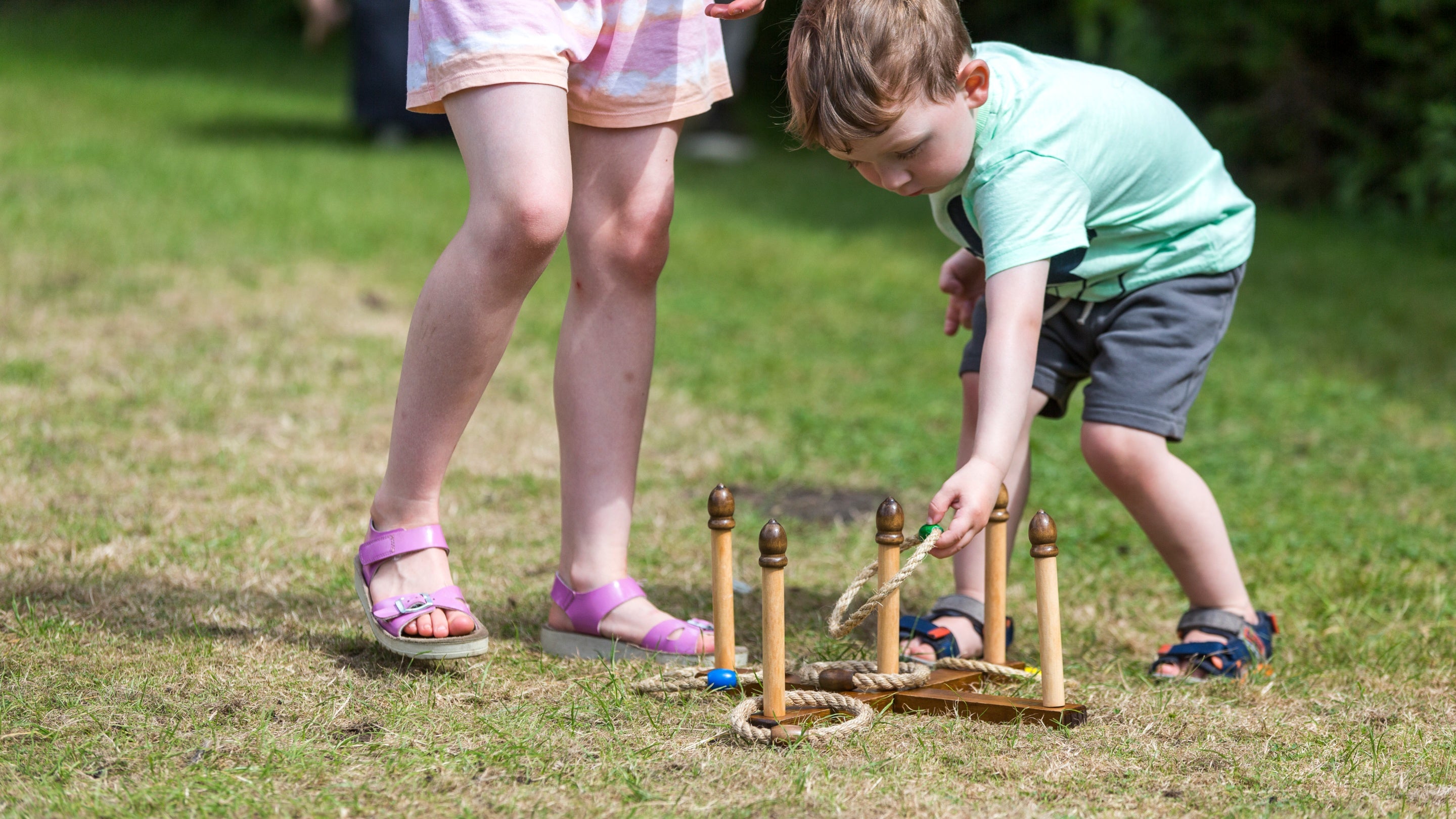 Children play ring toss on the lawn.