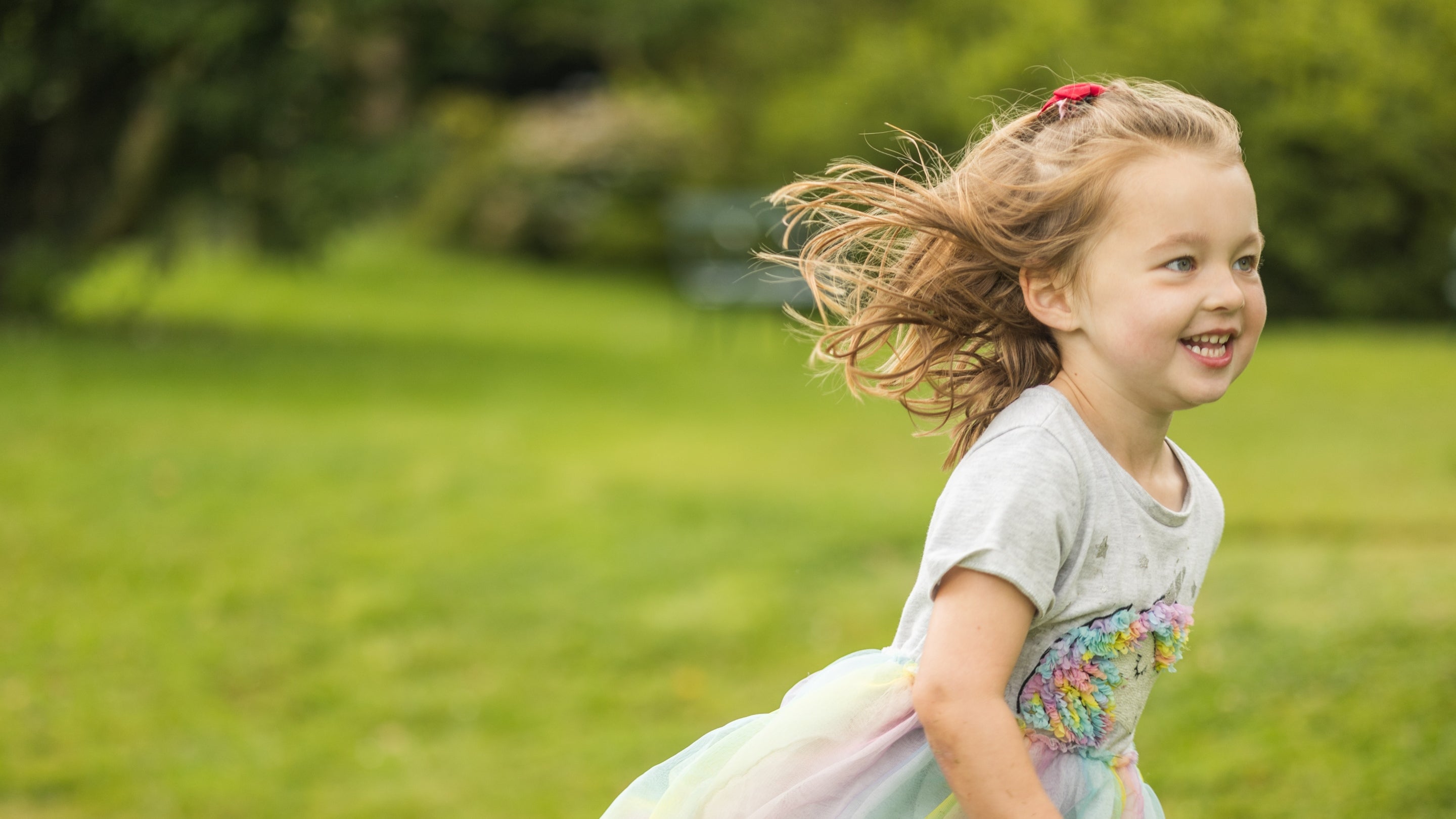 A young child runs across grass.