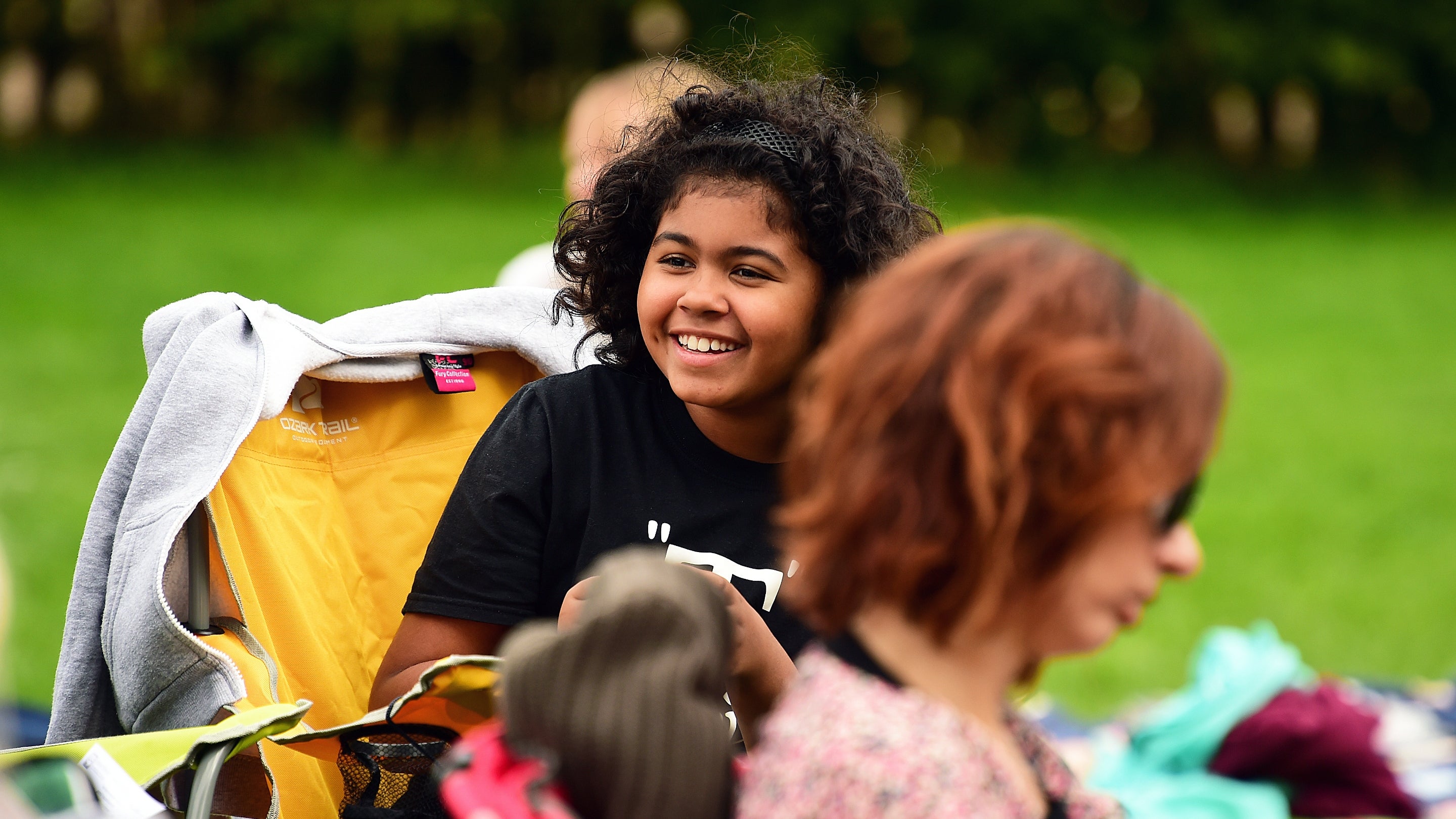 A visitor sits as part of a crowd at an outdoor event.