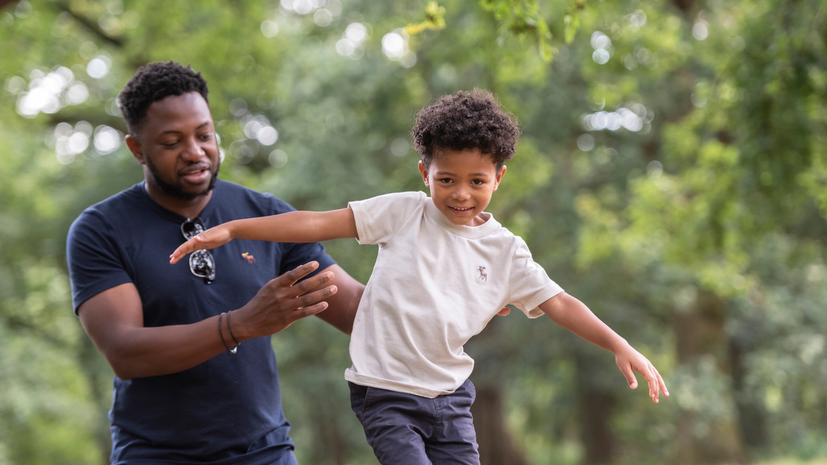 A father helps his son balance on a balance beam