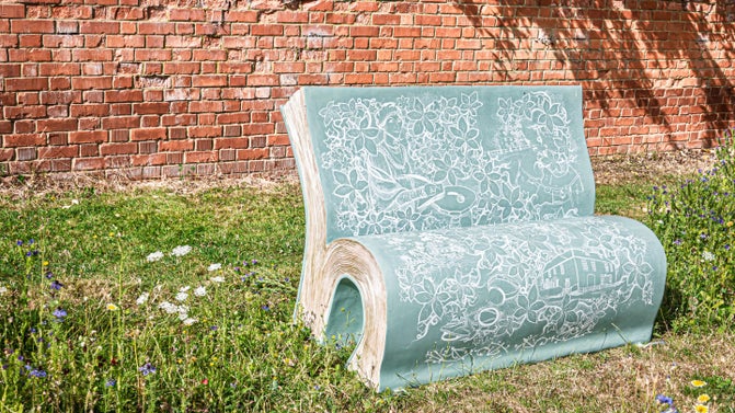 A bench in the shape of a book and decorated by an artist.