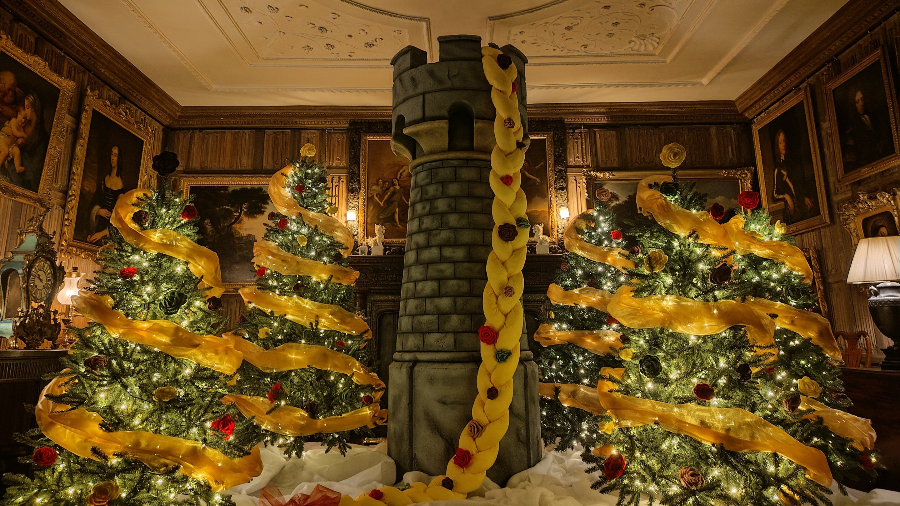 In a festive display a tower with Rapunzel's long blonde plait sits between sparkling Christmas trees in the Dining Parlour at The Vyne.