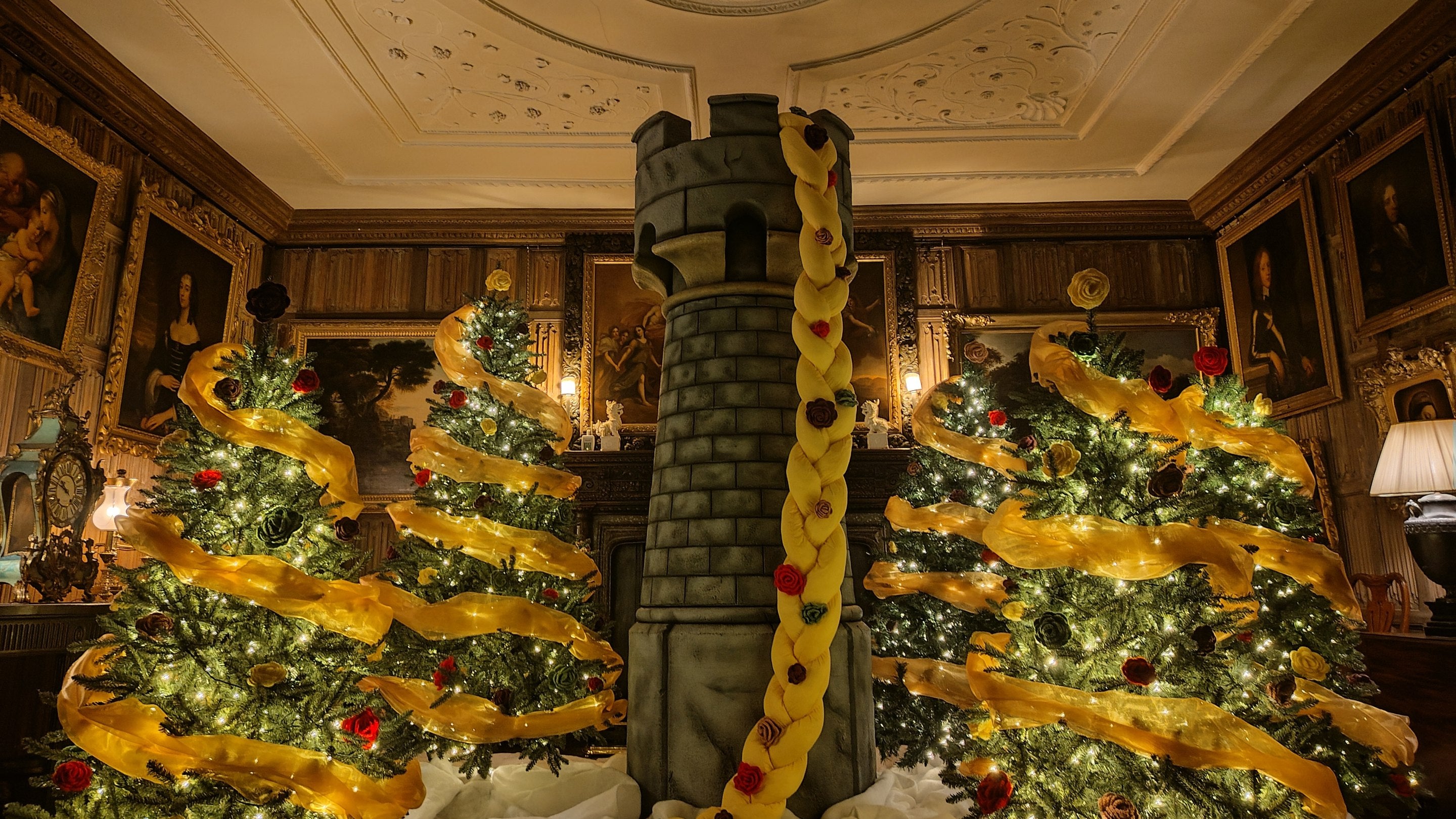 In a festive display a tower with Rapunzel's long blonde plait sits between sparkling Christmas trees in the Dining Parlour at The Vyne.