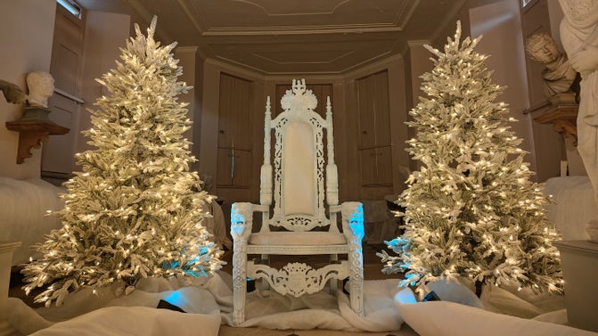 Twinkling snowy trees sit either side of a white throne.