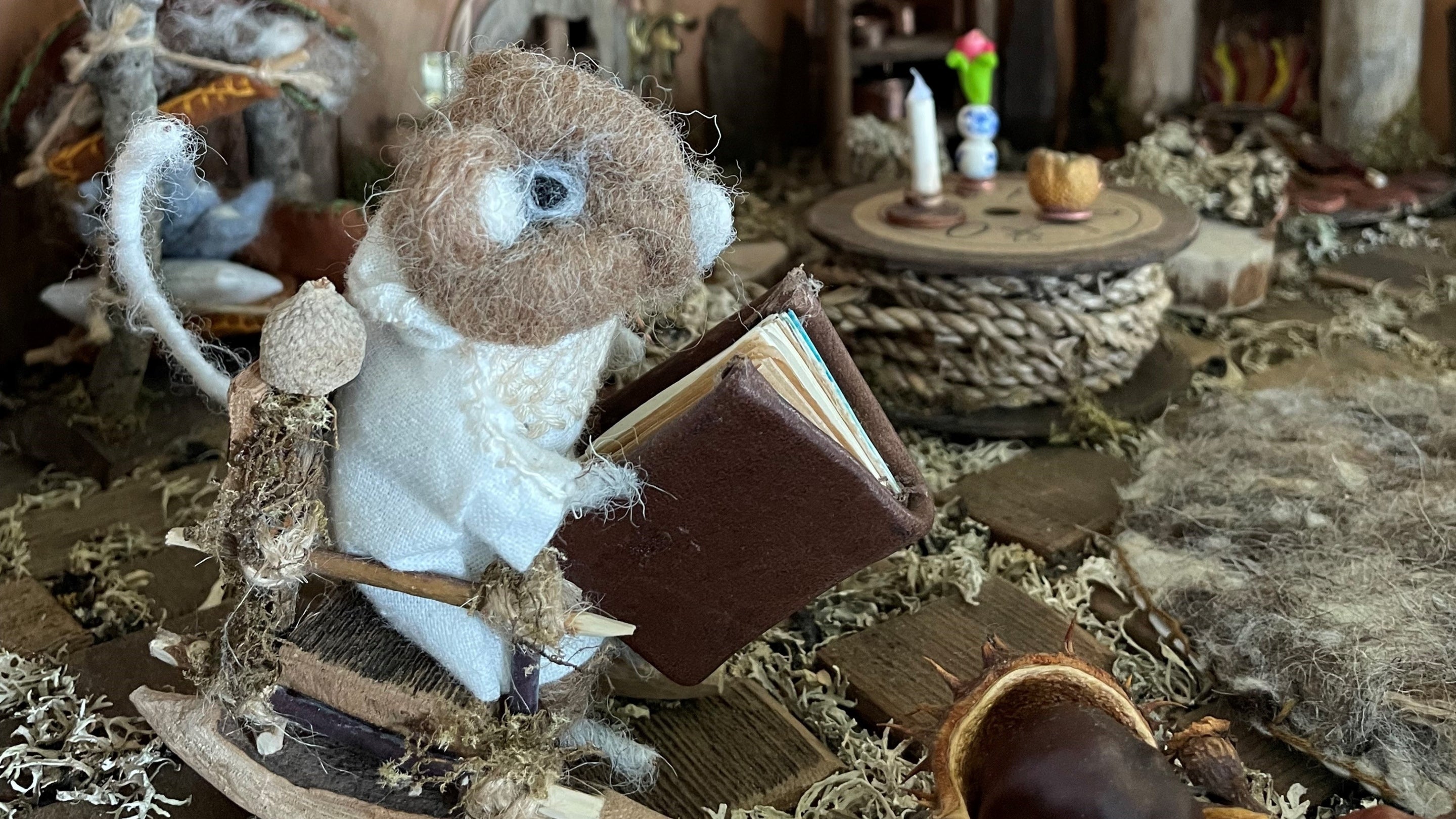 A felted mouse sitting in a chair reading a book at Bembridge Windmill