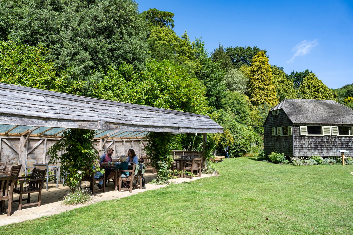 Family eating in the tea garden at Mottistone Gardens, under the shelter, on a sunny day.
