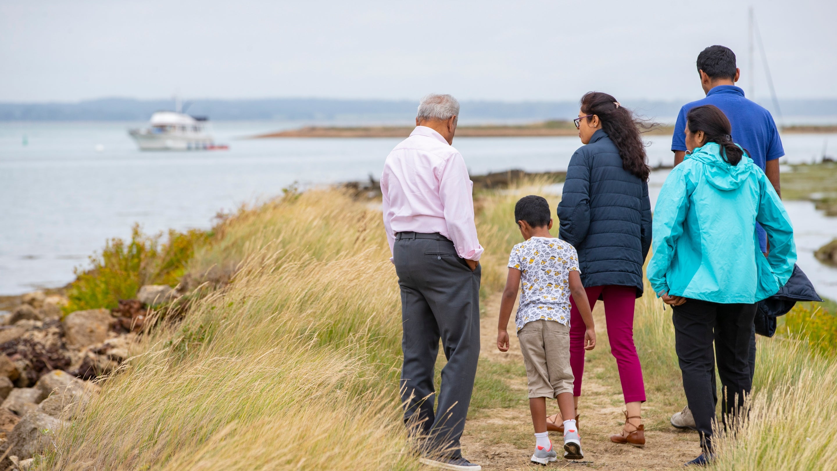 Family walking together by the harbour at Newtown National Nature Reserve, Isle of Wight