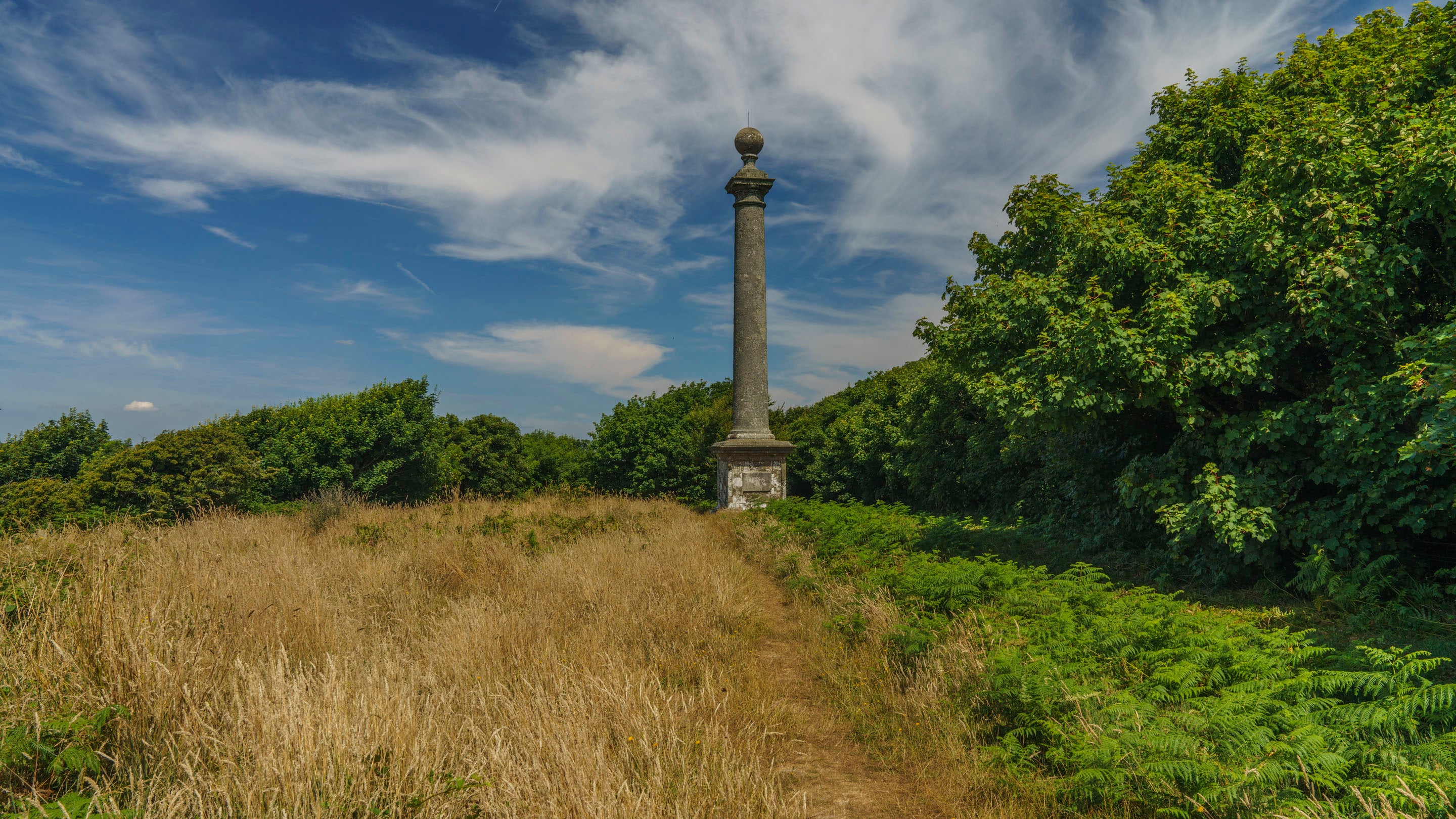 A bright spring day with blue skies behind the pillar of the Hoy Monument and bracken just starting to appear