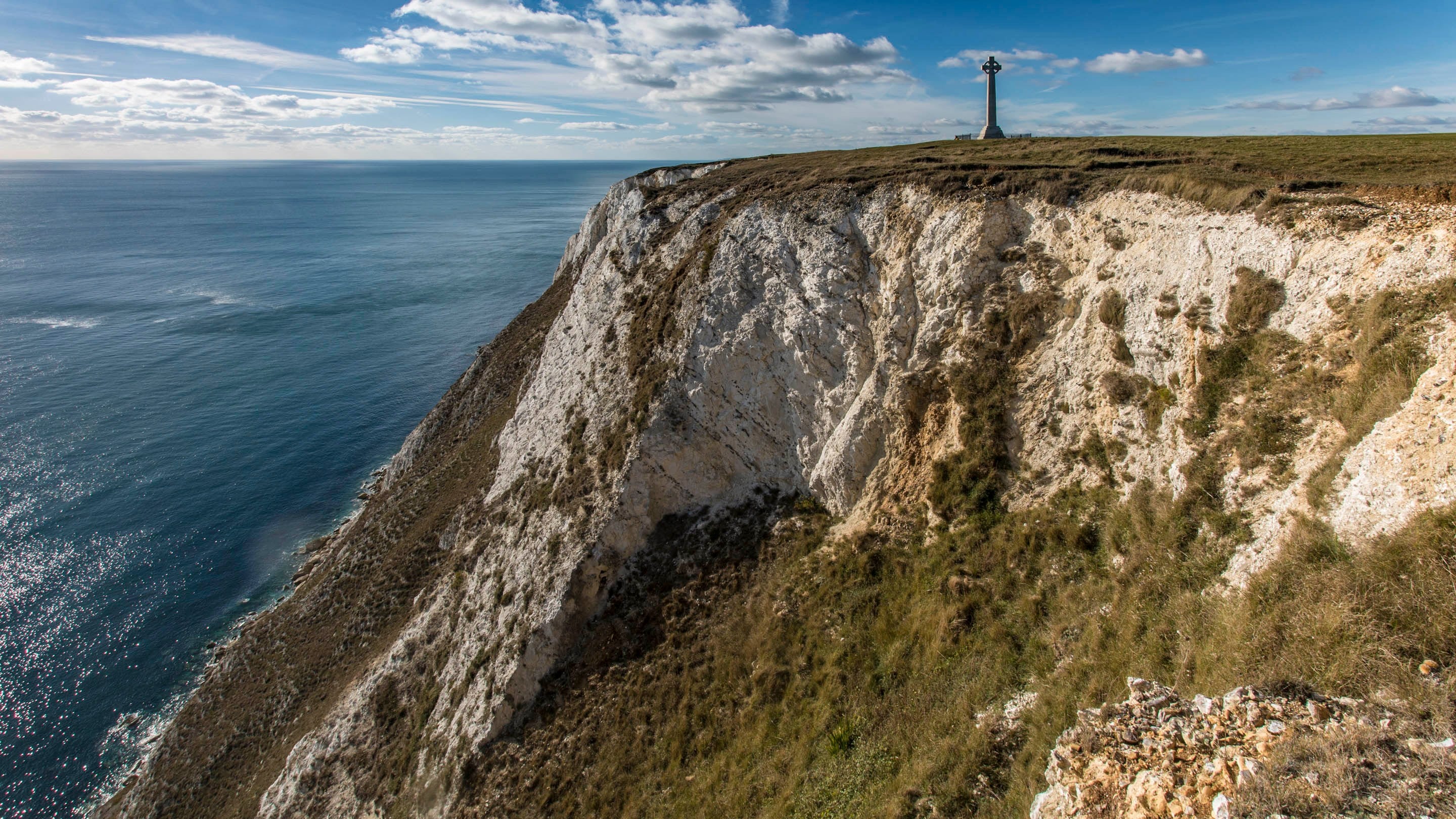 The Tennyson Monument stands proudly on top of the white cliffs with calm blue sea below