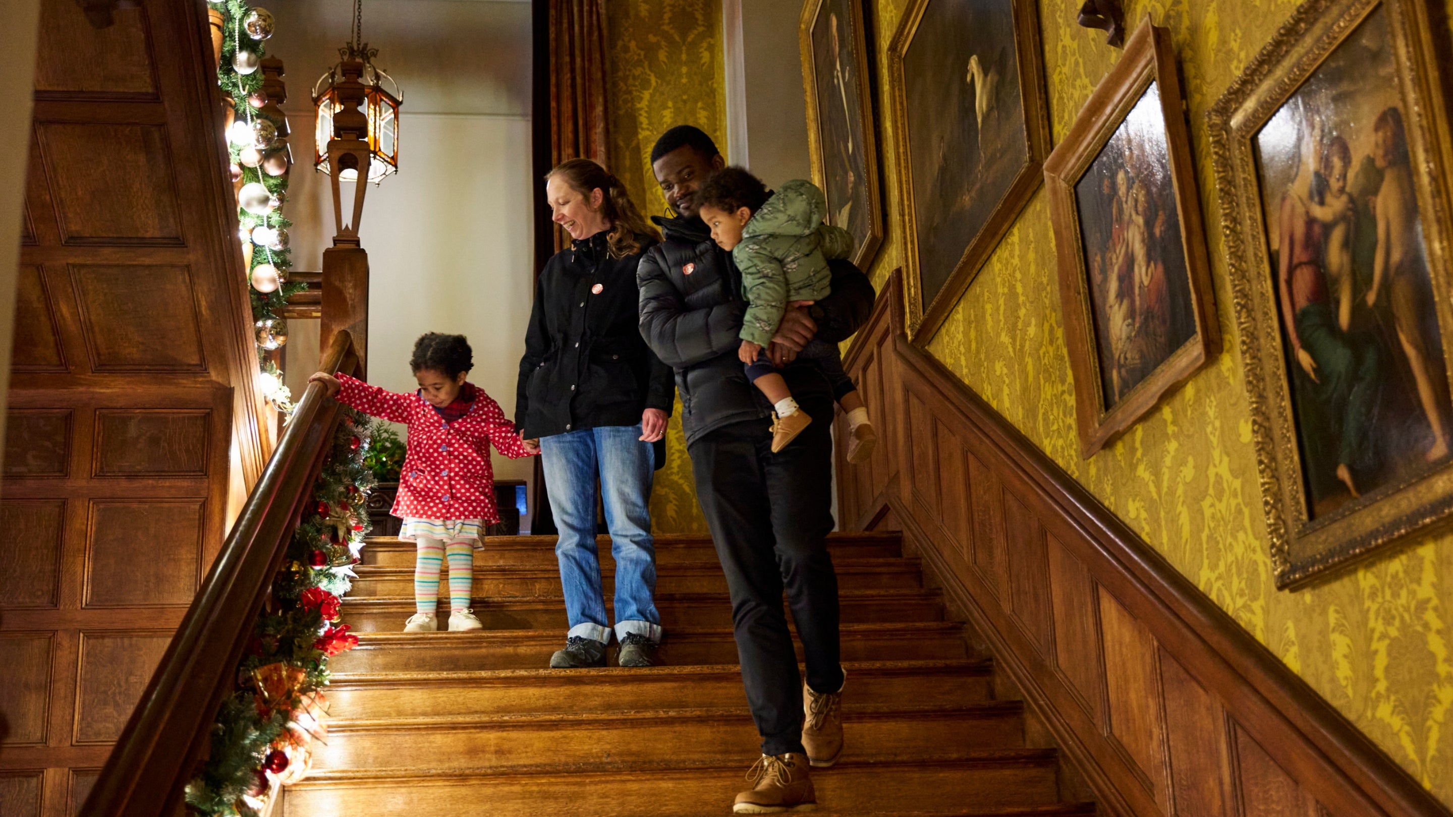Family walking down staircase with Christmas decorations at Scotney Castle, Kent