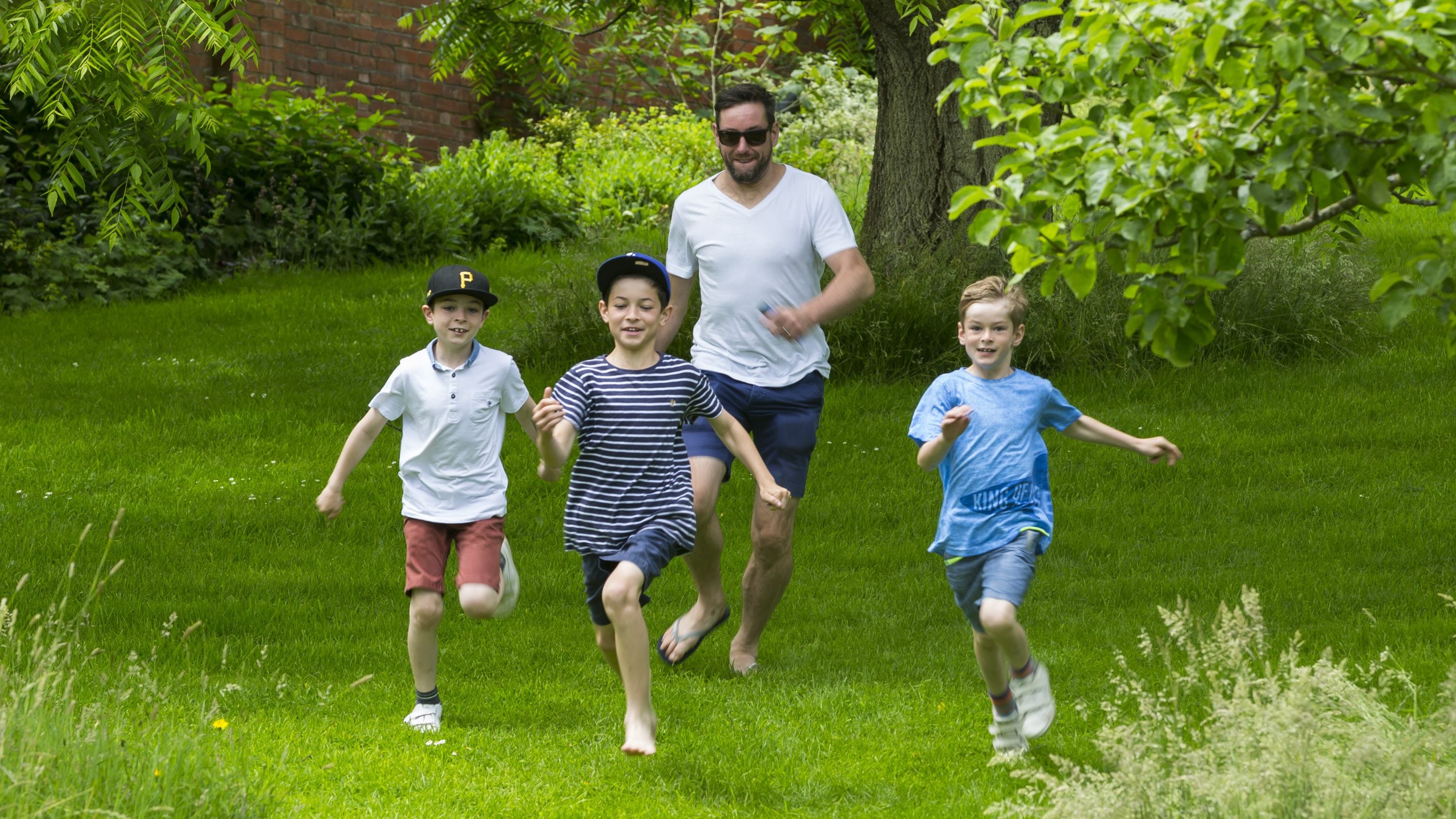 Father and his three sons playing chase in the garden at Chartwell.