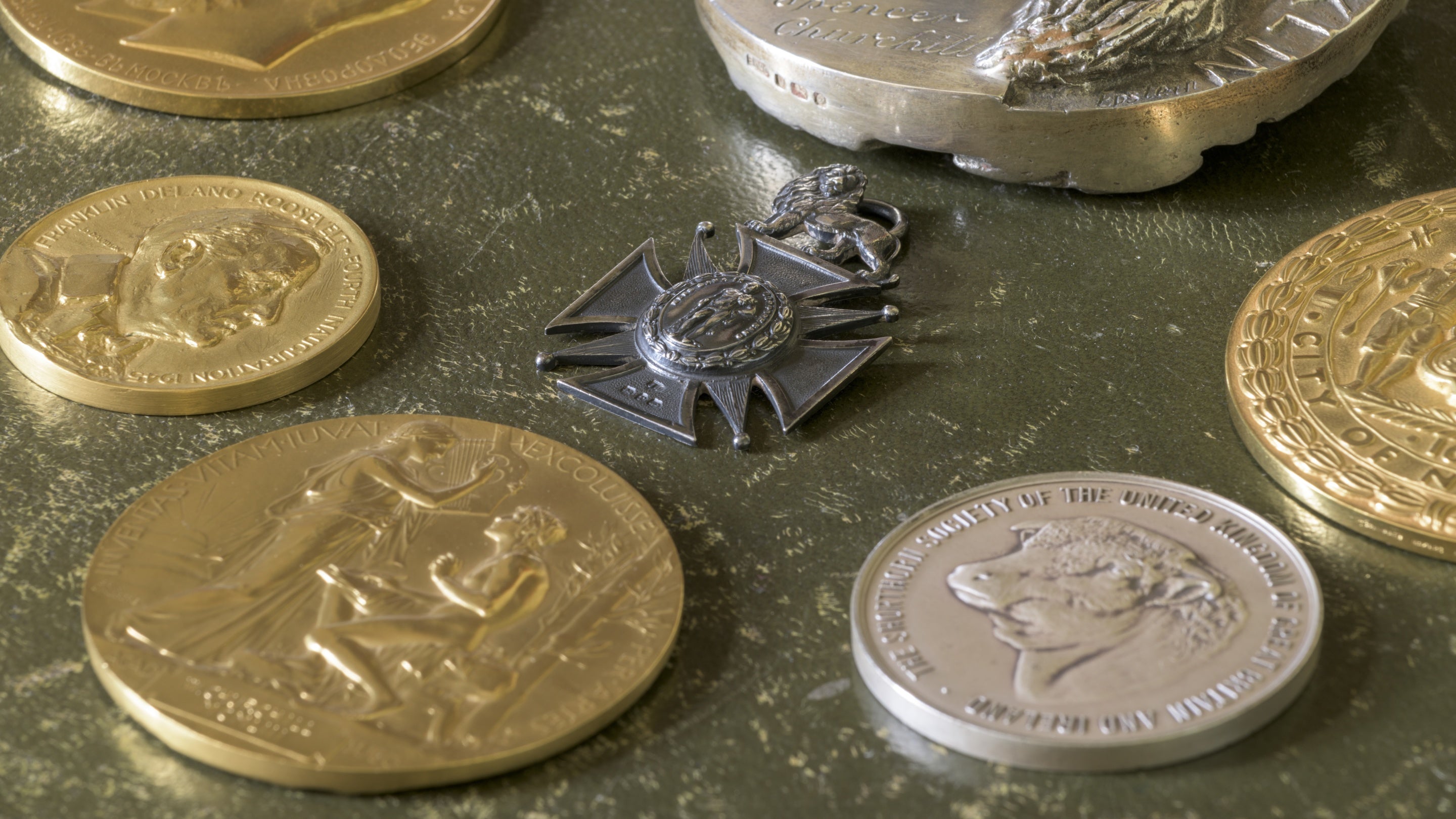 Silver and gold coins and a cross shaped pendant laid out on a table