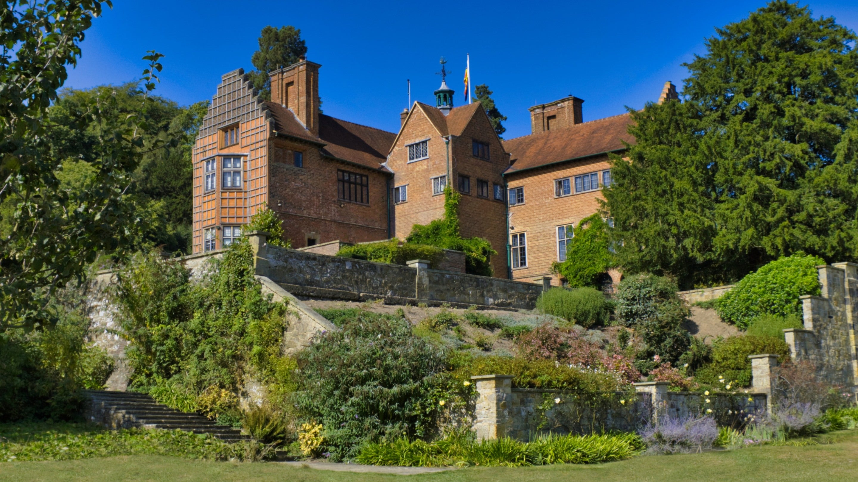 Sunny view of the red brick house, lawn and trees at Chartwell
