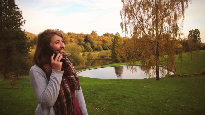 Visitor to Chartwell listens to audio guide in the gardens, swimming pool in background