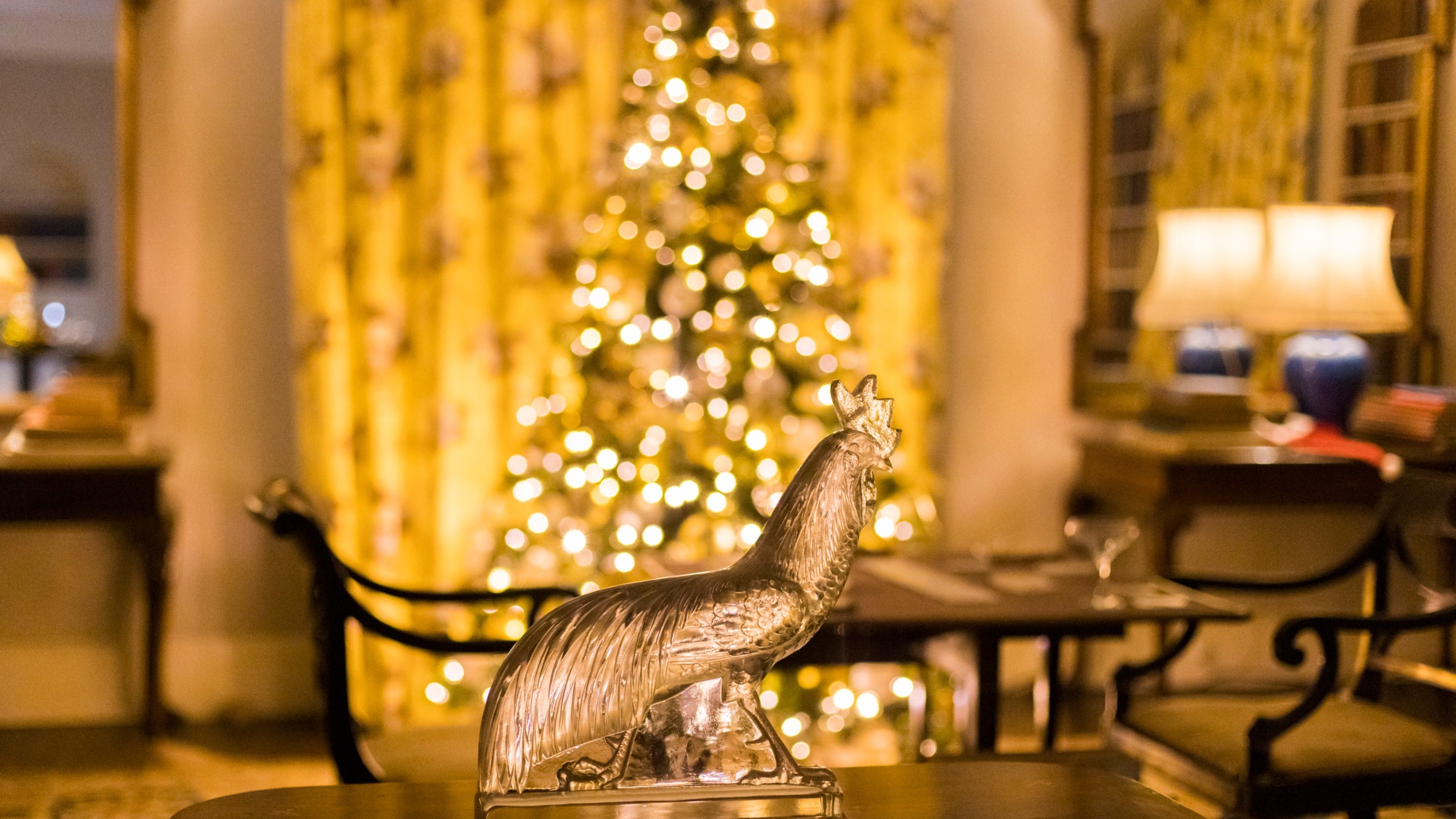 The Lalique glass Cockerel statue with the Christmas tree in the background in the Drawing Room at Chartwell, Kent