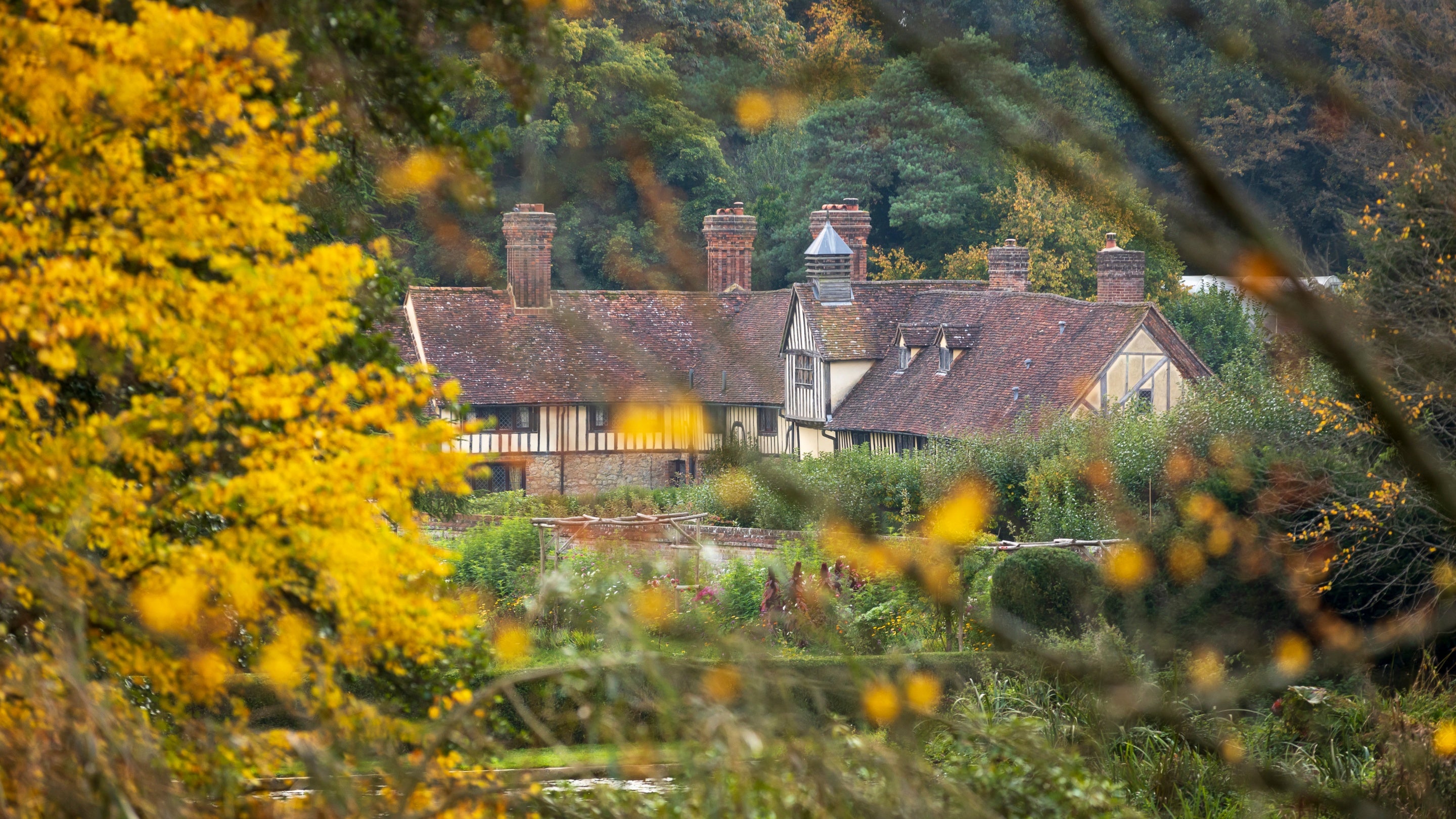 Autumn view of the gardens and Mote Cottages at Ightham Mote, Kent NT1G6OT