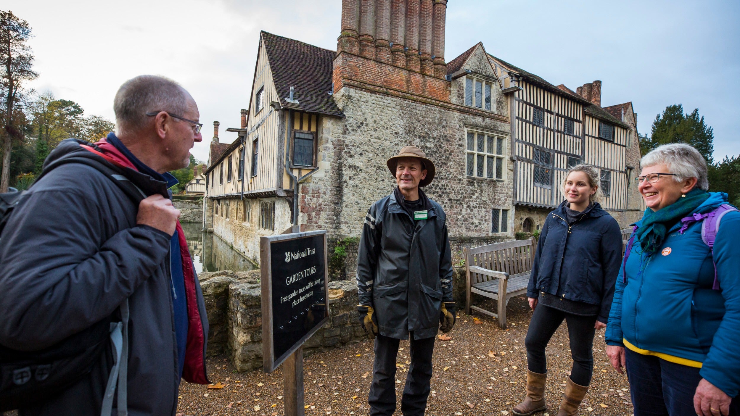 Group of visitors listening to Garden Tour guide outside Ightham Mote Kent