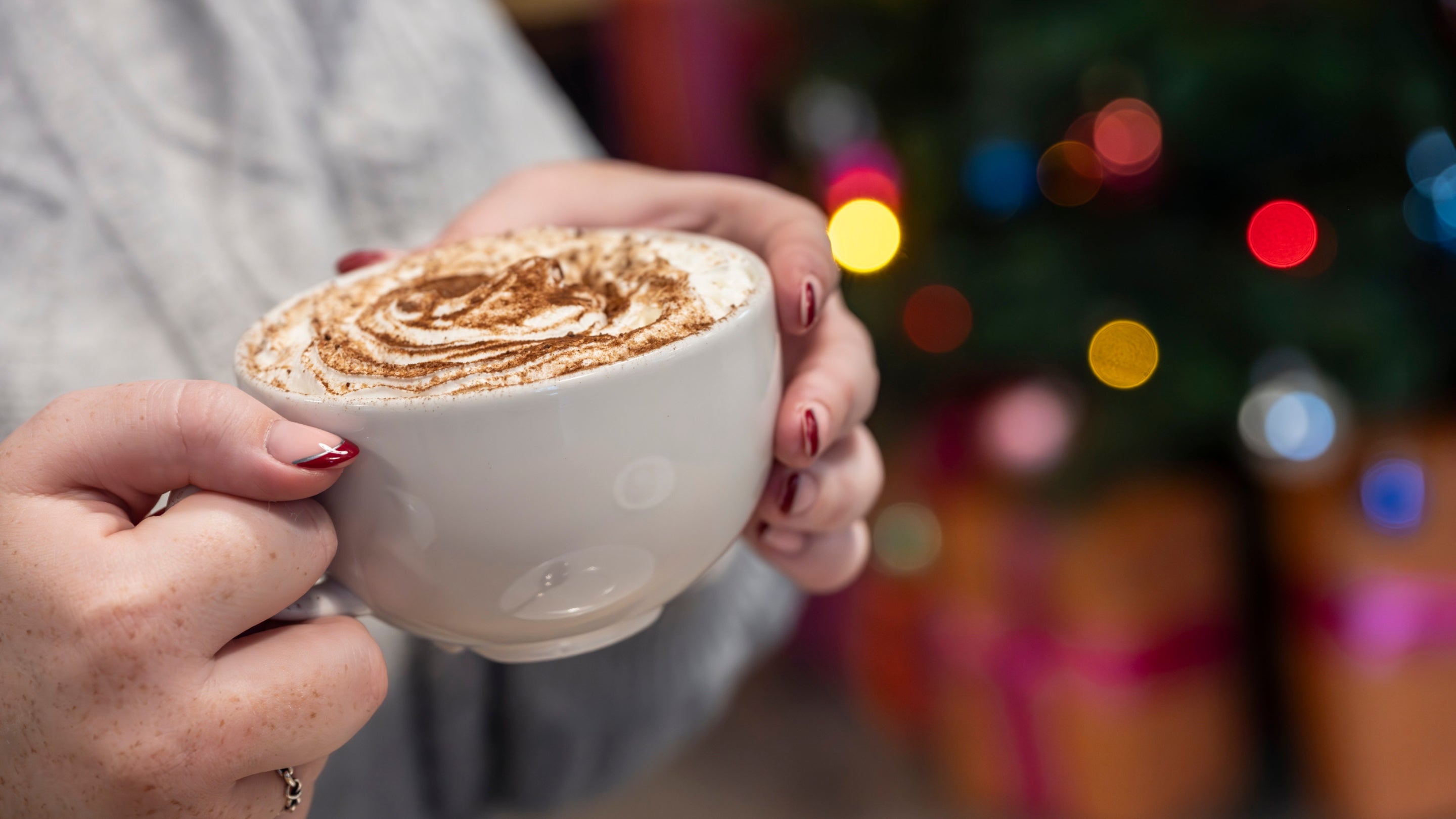 Visitor holding coffee cup in front of Christmas tree