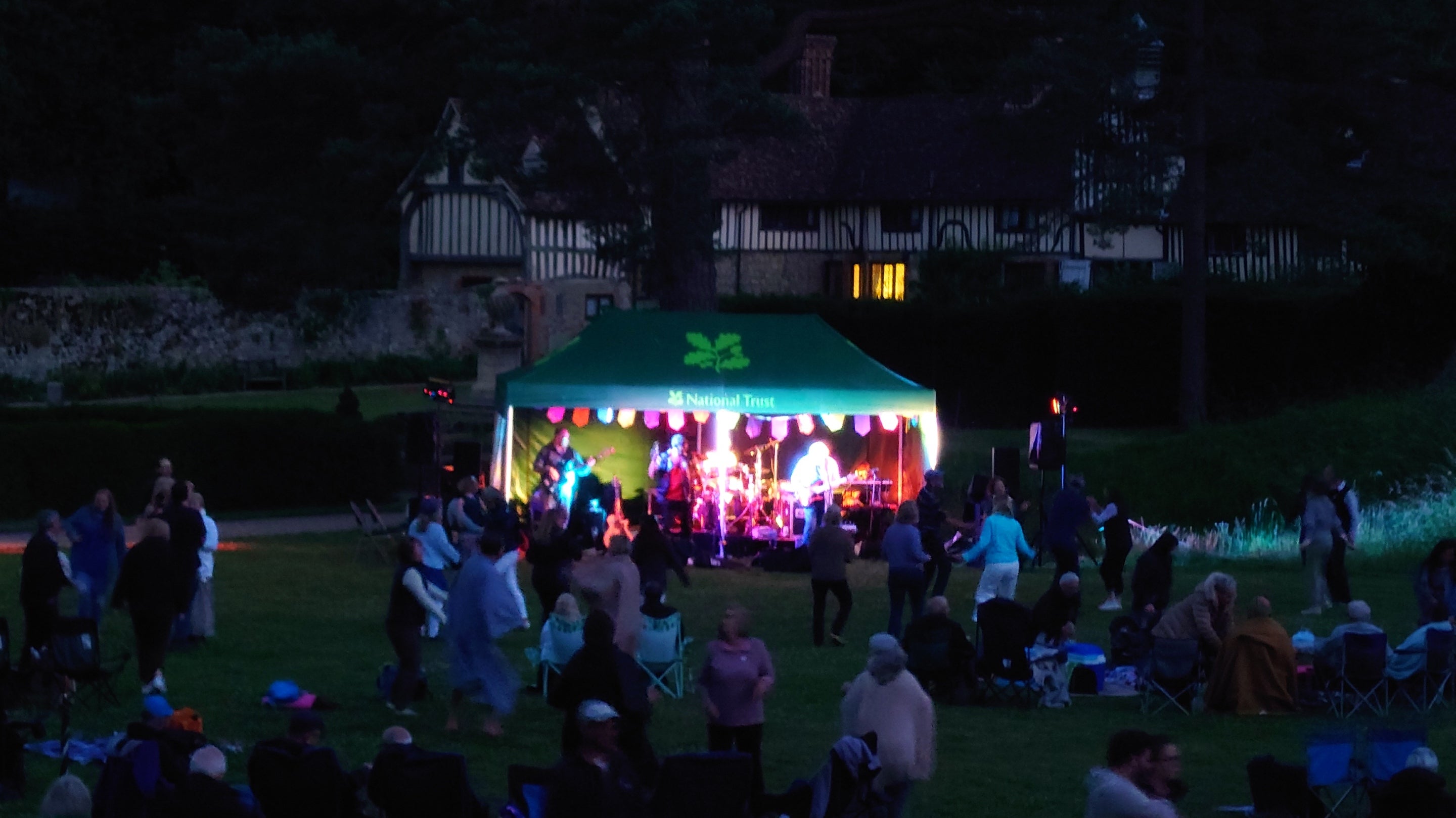 Audience enjoying The Dial band after dark at Ightham Mote