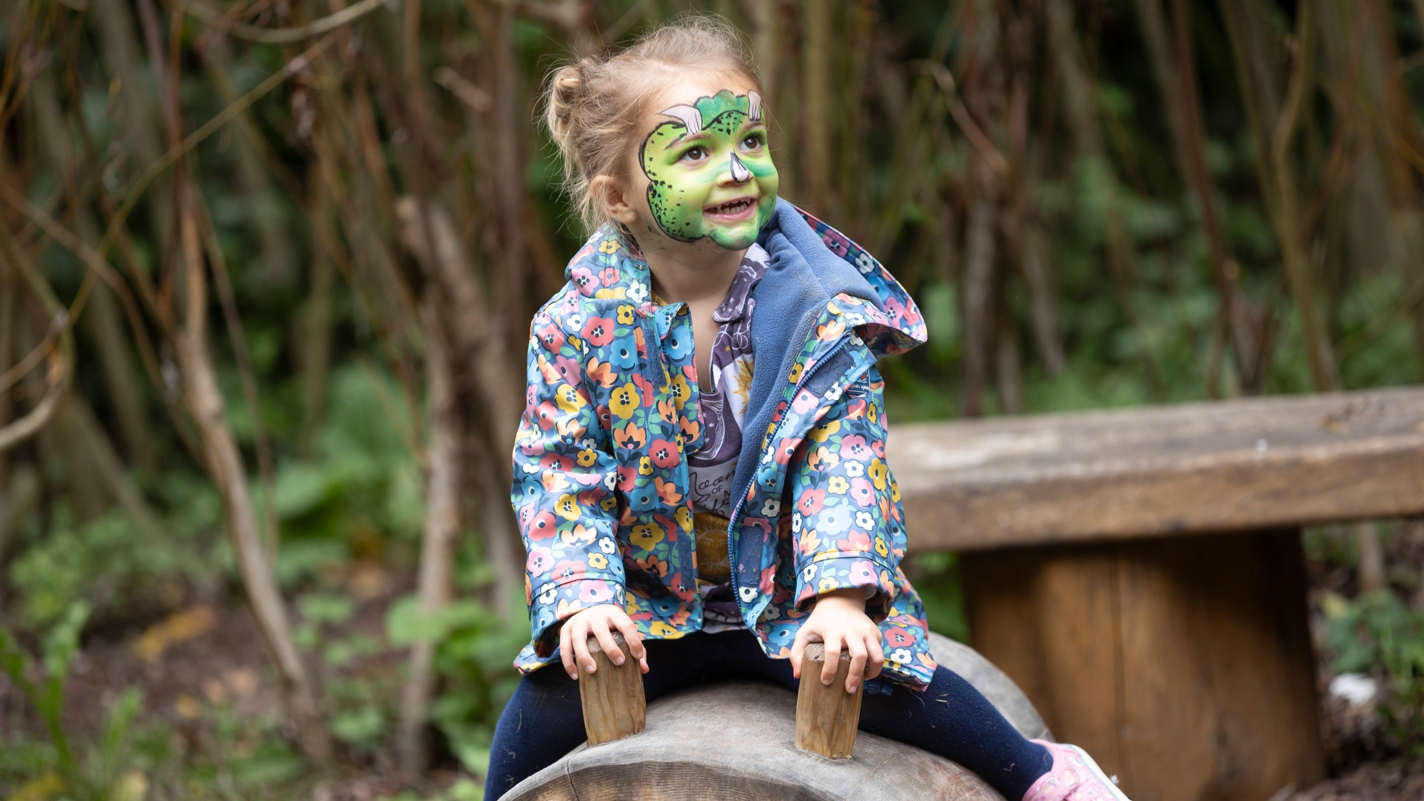Child sits on wooden piggy in natural play area at Ightham Mote, Kent