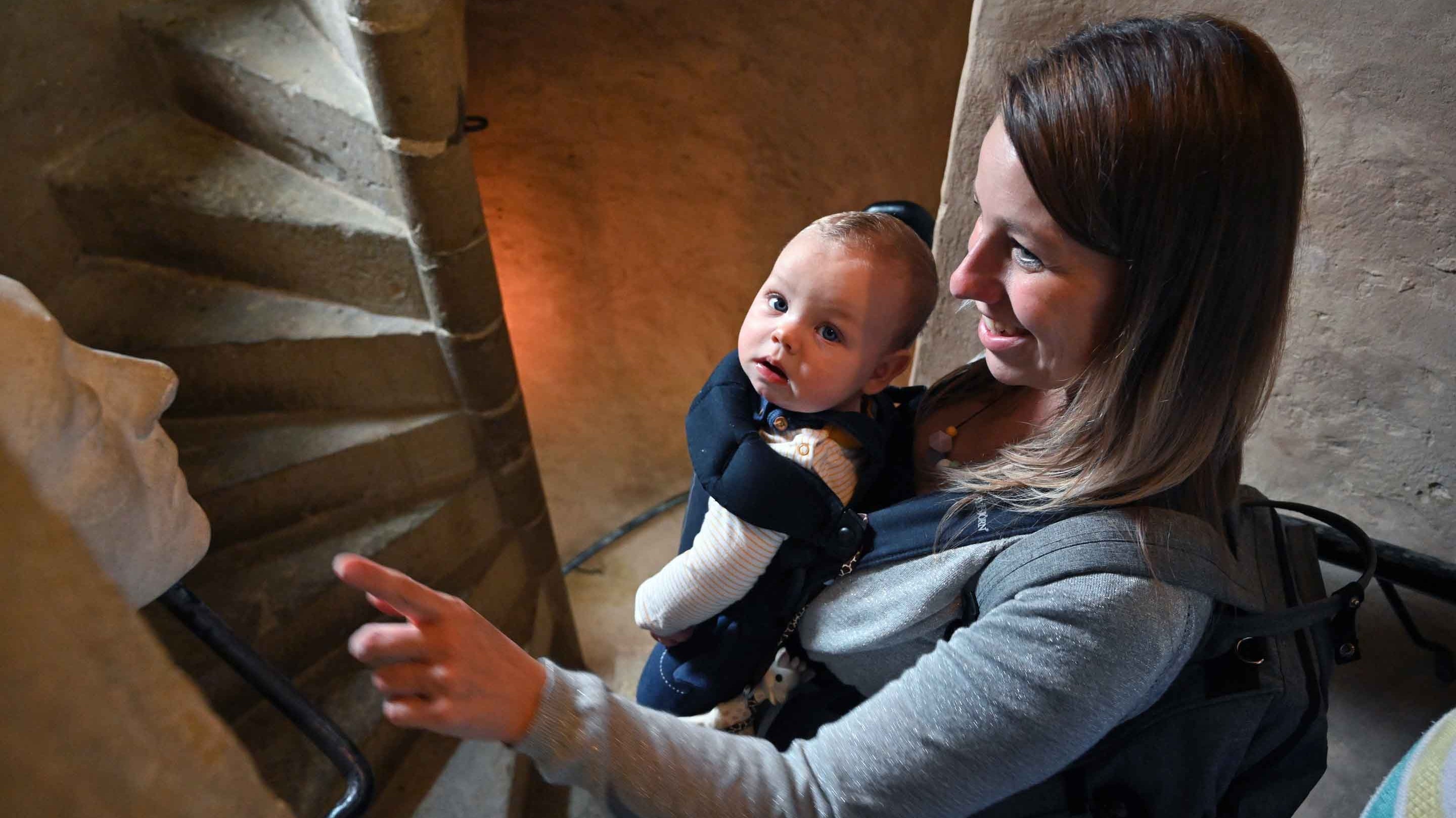 A mum and her baby climbing the spiral stone staircase inside the Gatehouse Tower at Knole in Kent