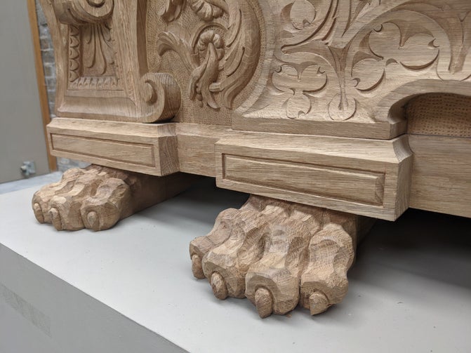 A close up of the carved feet on a large piece of wooden furniture. The feet are in the shape of lion paws.
