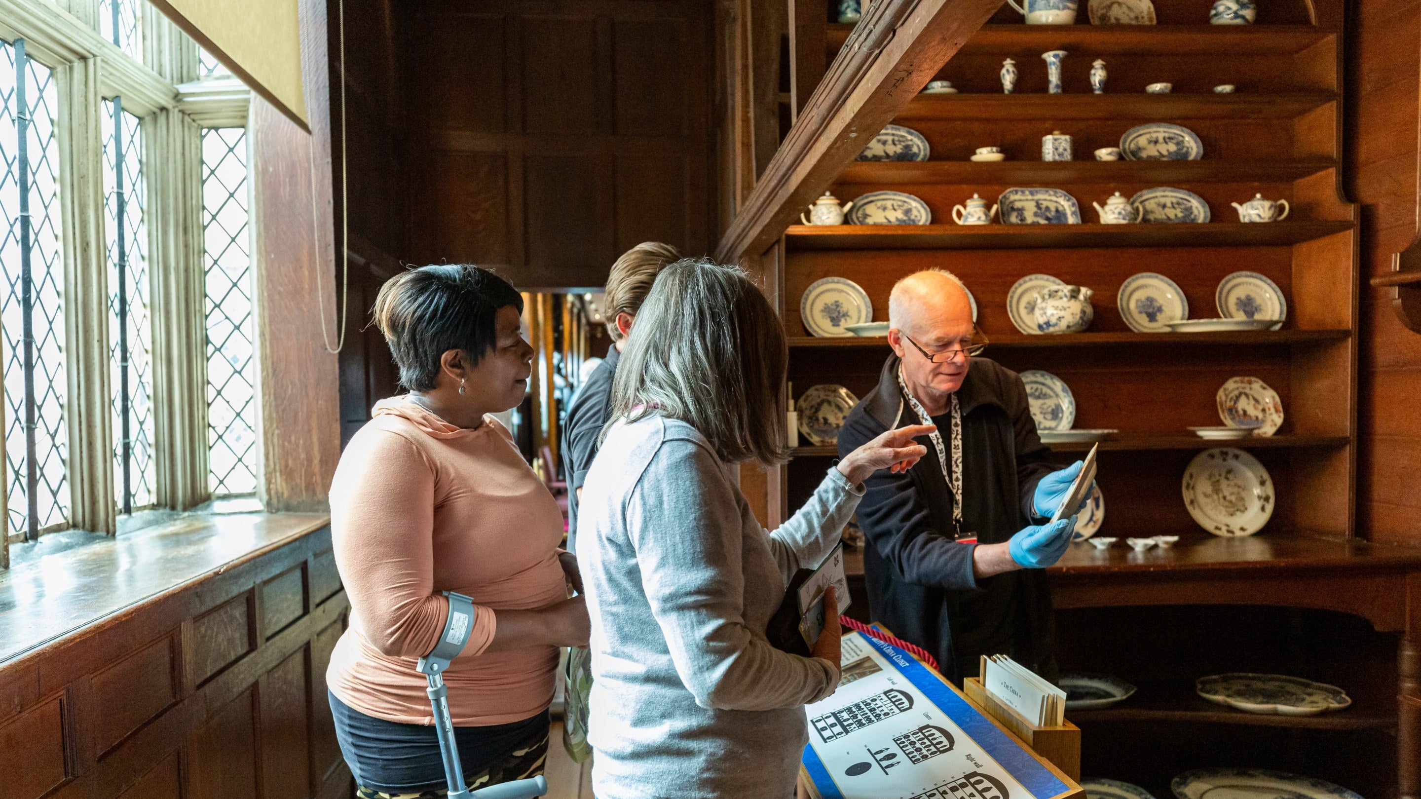 Volunteer showing the decoration on a ceramic plate to visitors at Knole, Kent